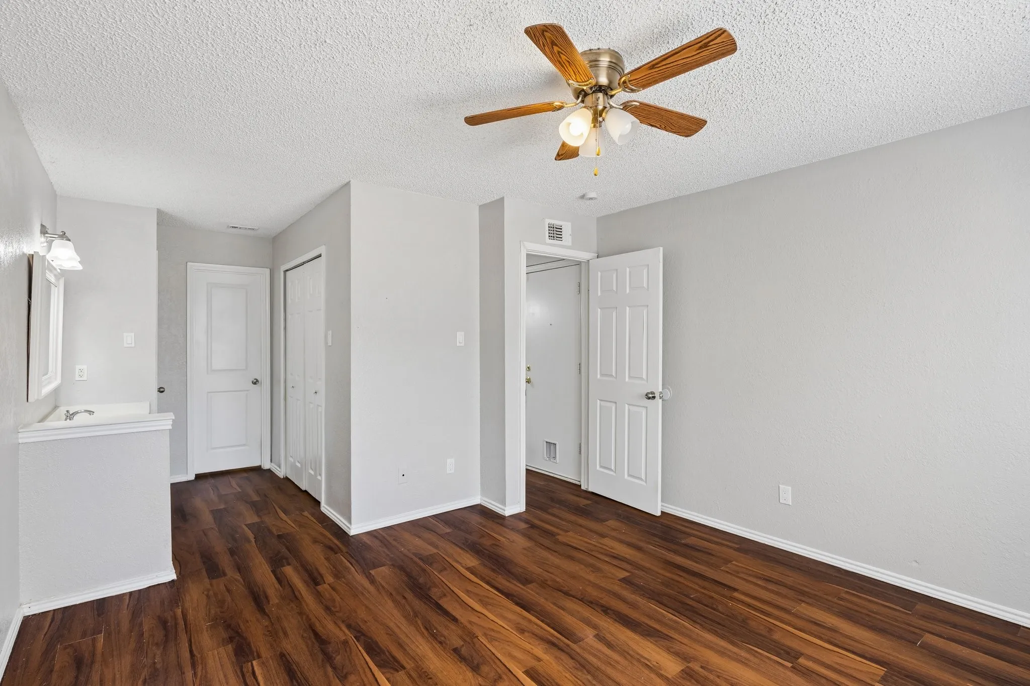 Wood-finish flooring, ceiling fan with light fixture, built-in vanity with sink, and bi-fold closet doors