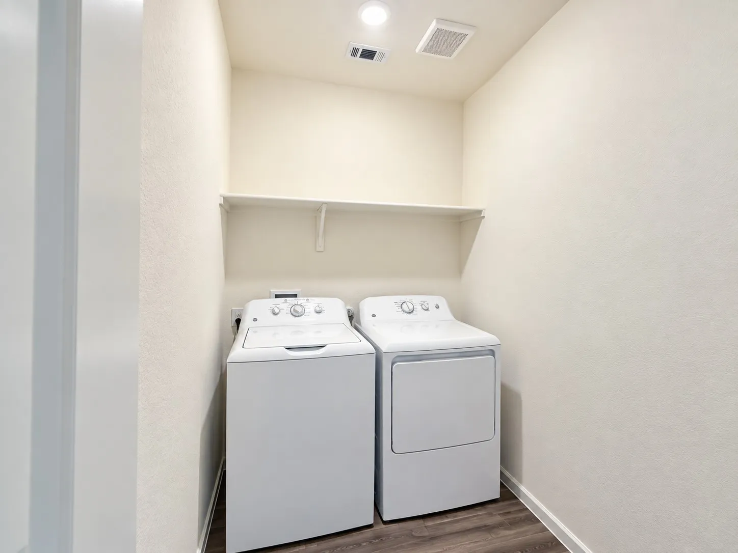Laundry area with wood-finish flooring and integrated shelving