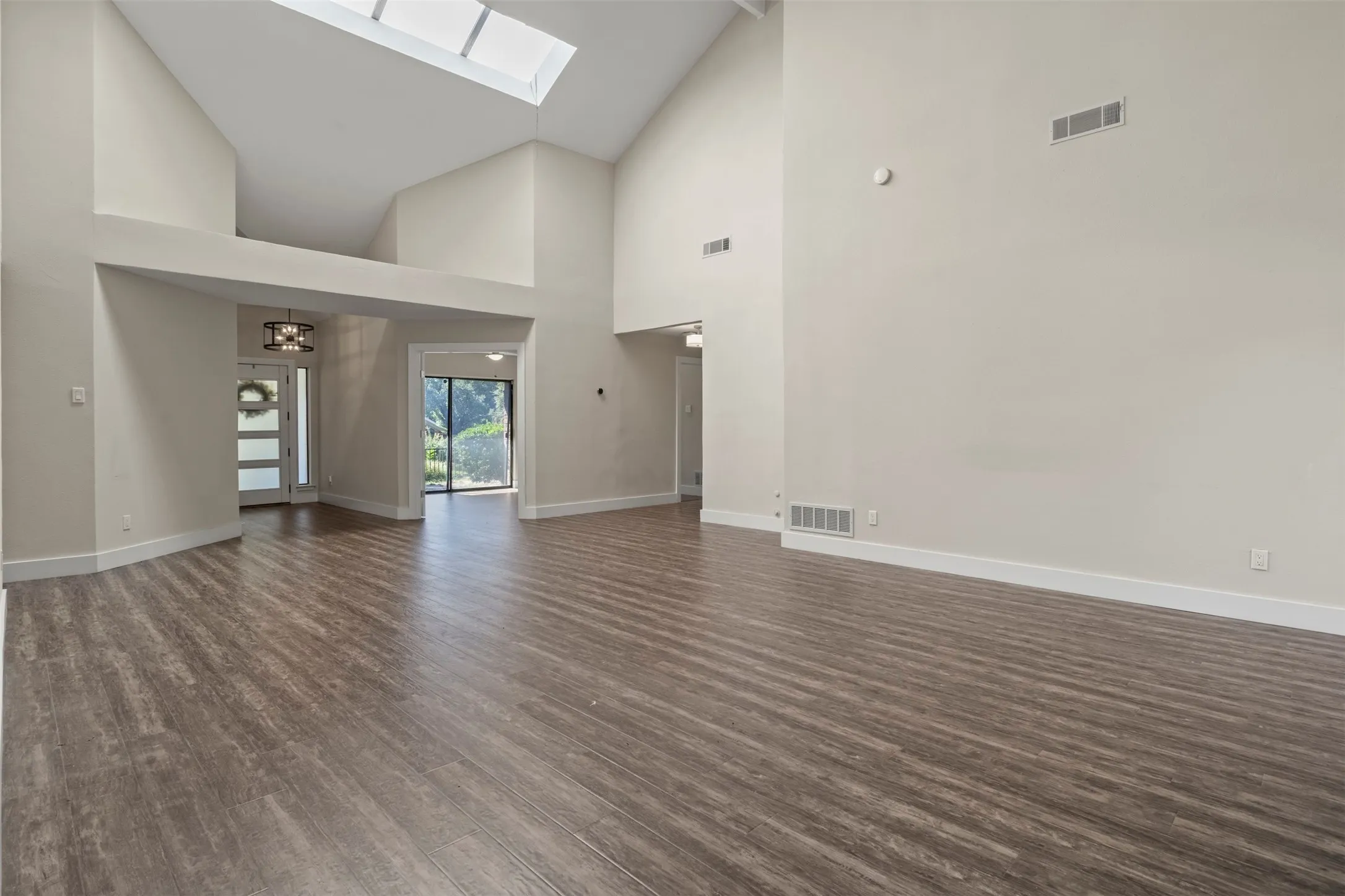 Vaulted ceilings, wood-finish flooring, and a skylight illuminate this expansive living area