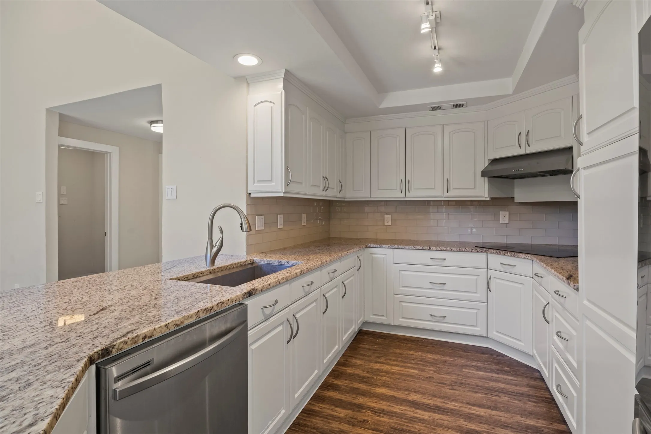 Kitchen featuring white cabinetry, granite countertops, a stainless steel sink with a gooseneck faucet, a subway tile backsplash