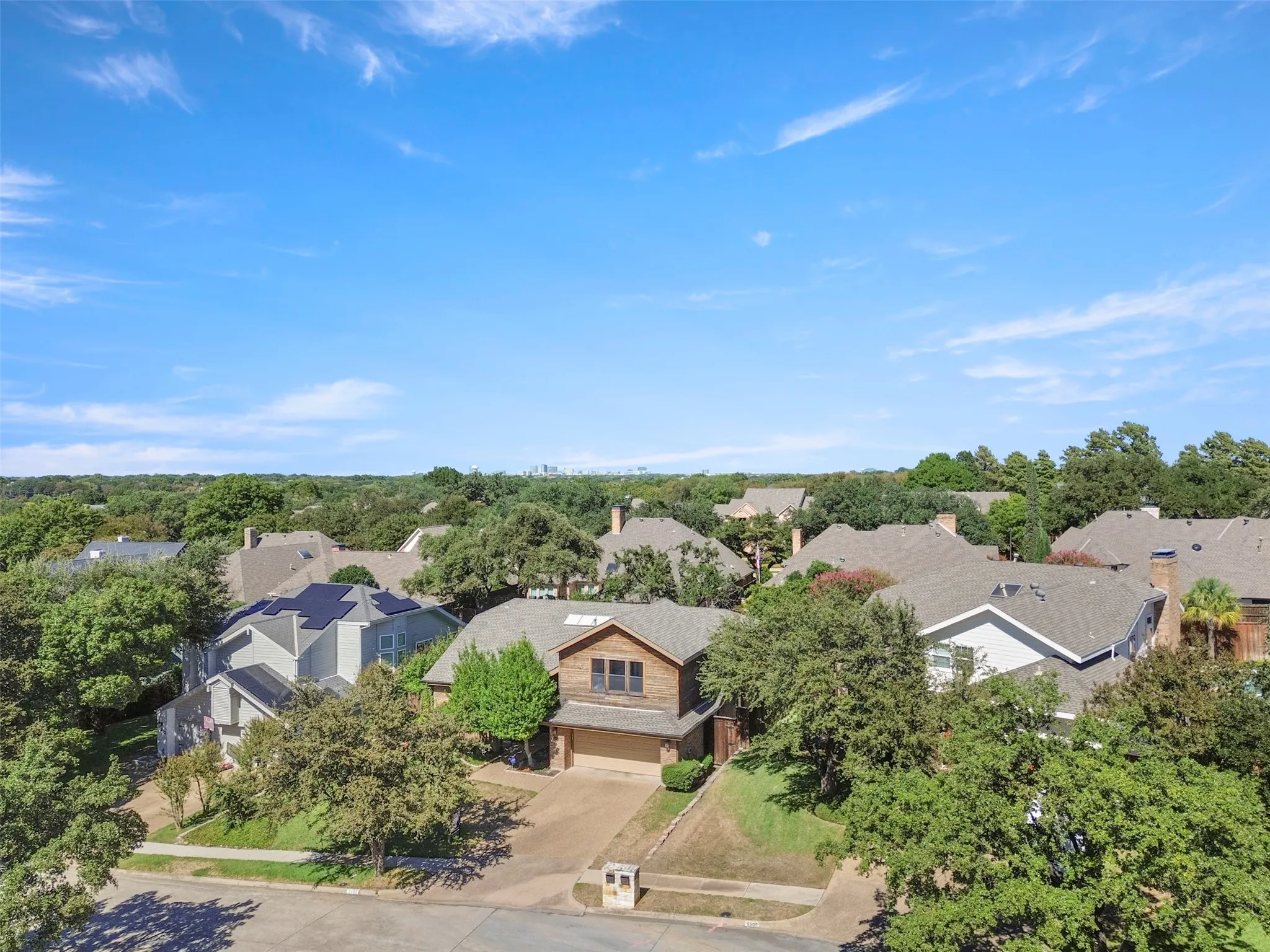 Two-story residence with an attached garage, featuring a shingled roof and mature landscaping