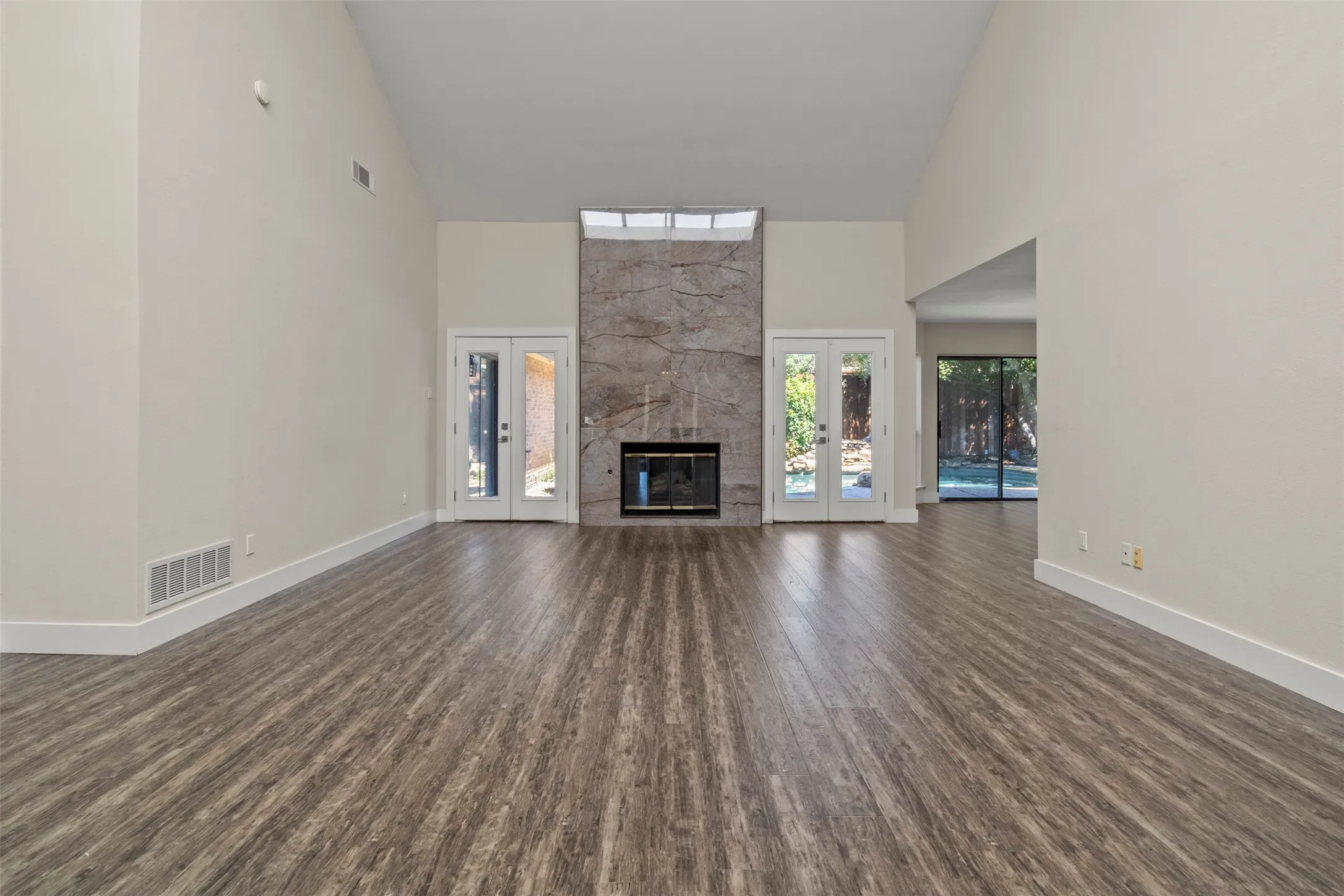 Vaulted ceilings, wood-finish flooring, and a stone-clad fireplace with a recessed firebox