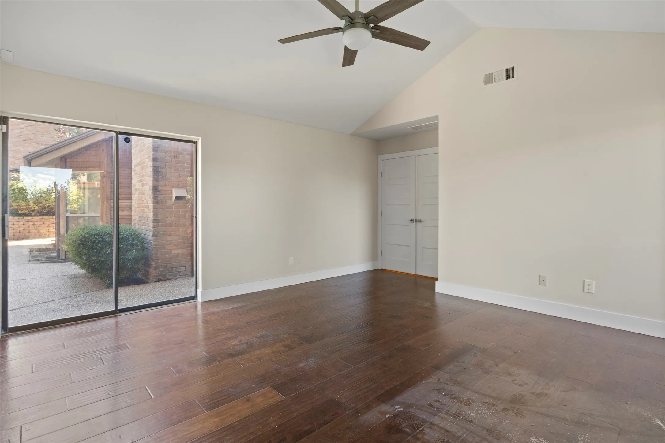 Vaulted ceiling with a ceiling fan, wood-finish flooring, and sliding glass doors