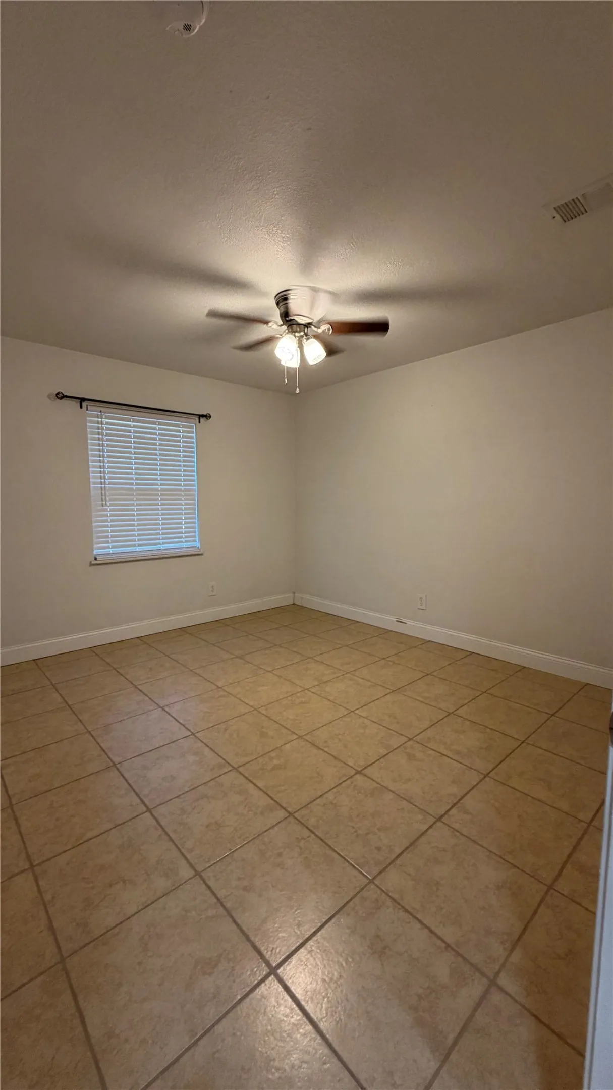 Tile flooring, neutral wall tones, window with blinds, and a ceiling fan with integrated lighting