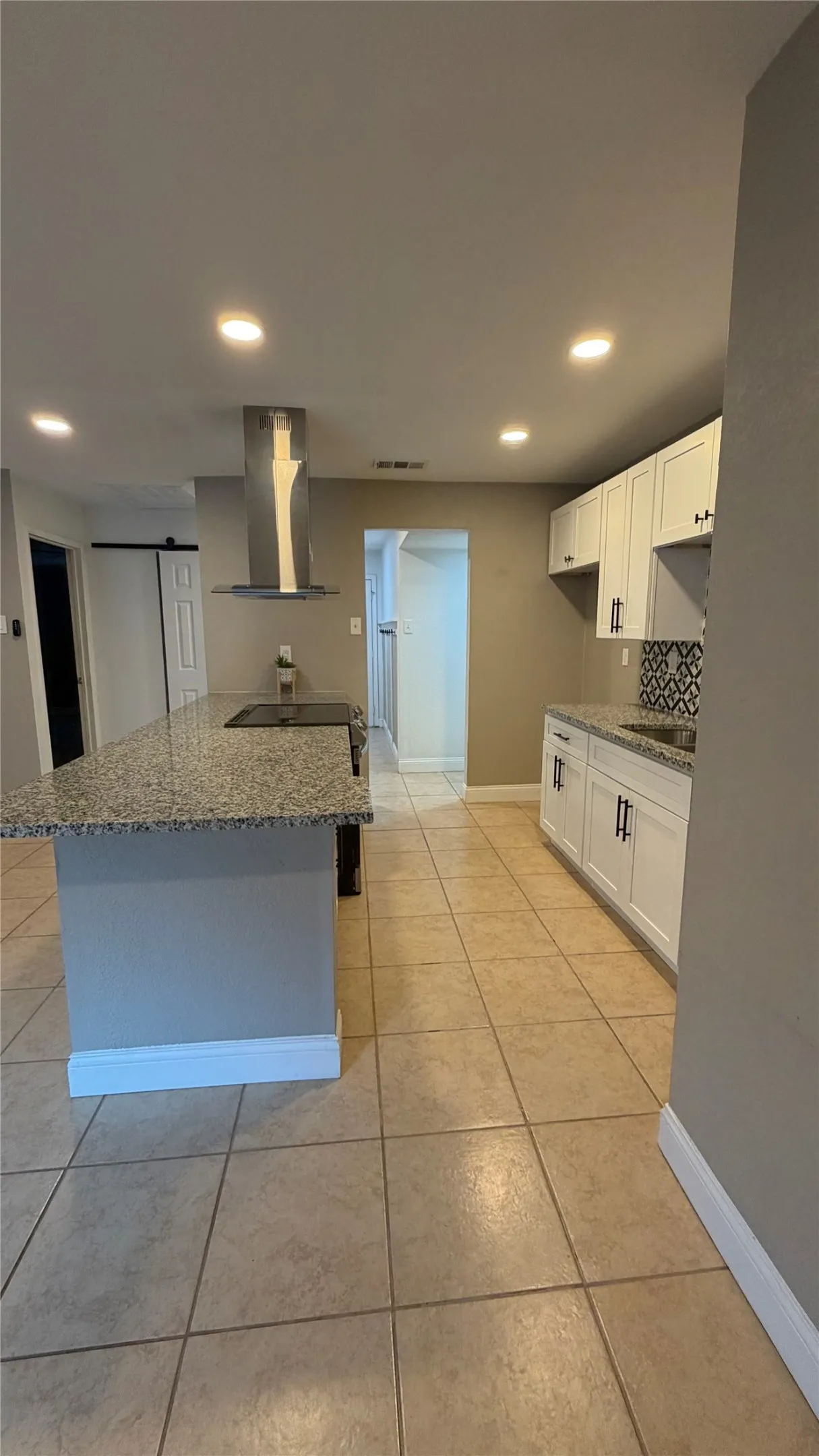 Kitchen featuring an island, recessed lighting, tile flooring, white cabinetry, and granite countertops