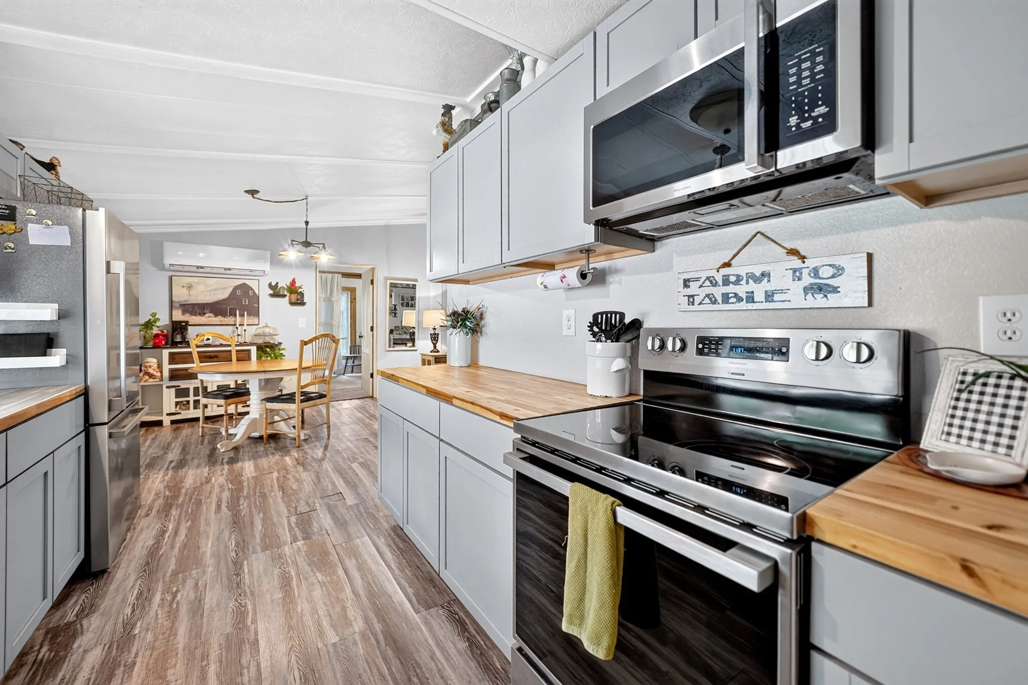 Kitchen featuring light gray cabinetry, wood-finish countertops, stainless steel appliances, and wood-finish flooring