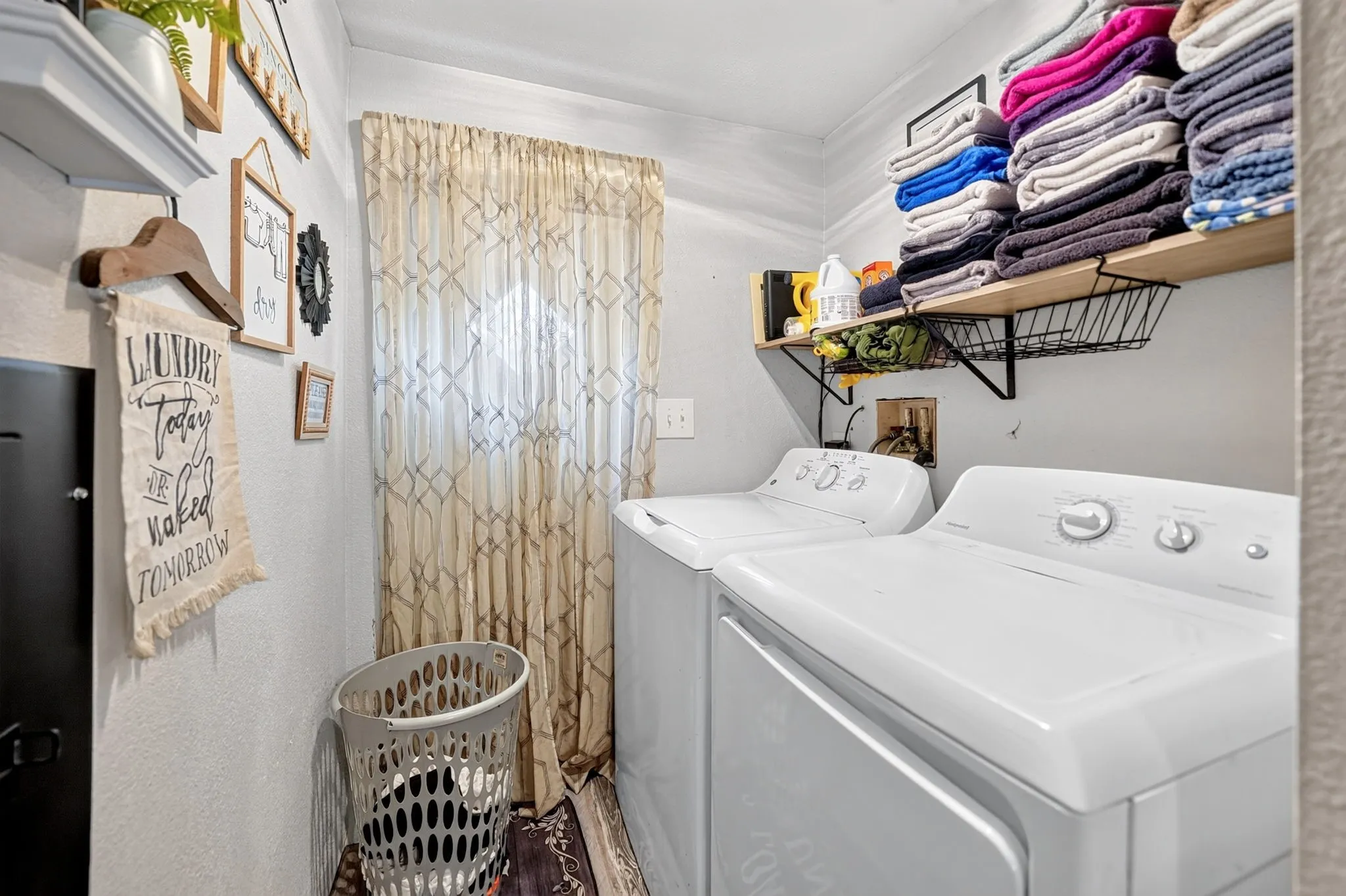 Laundry area featuring a full-size washer and dryer, built-in shelving, and a window with patterned drapes