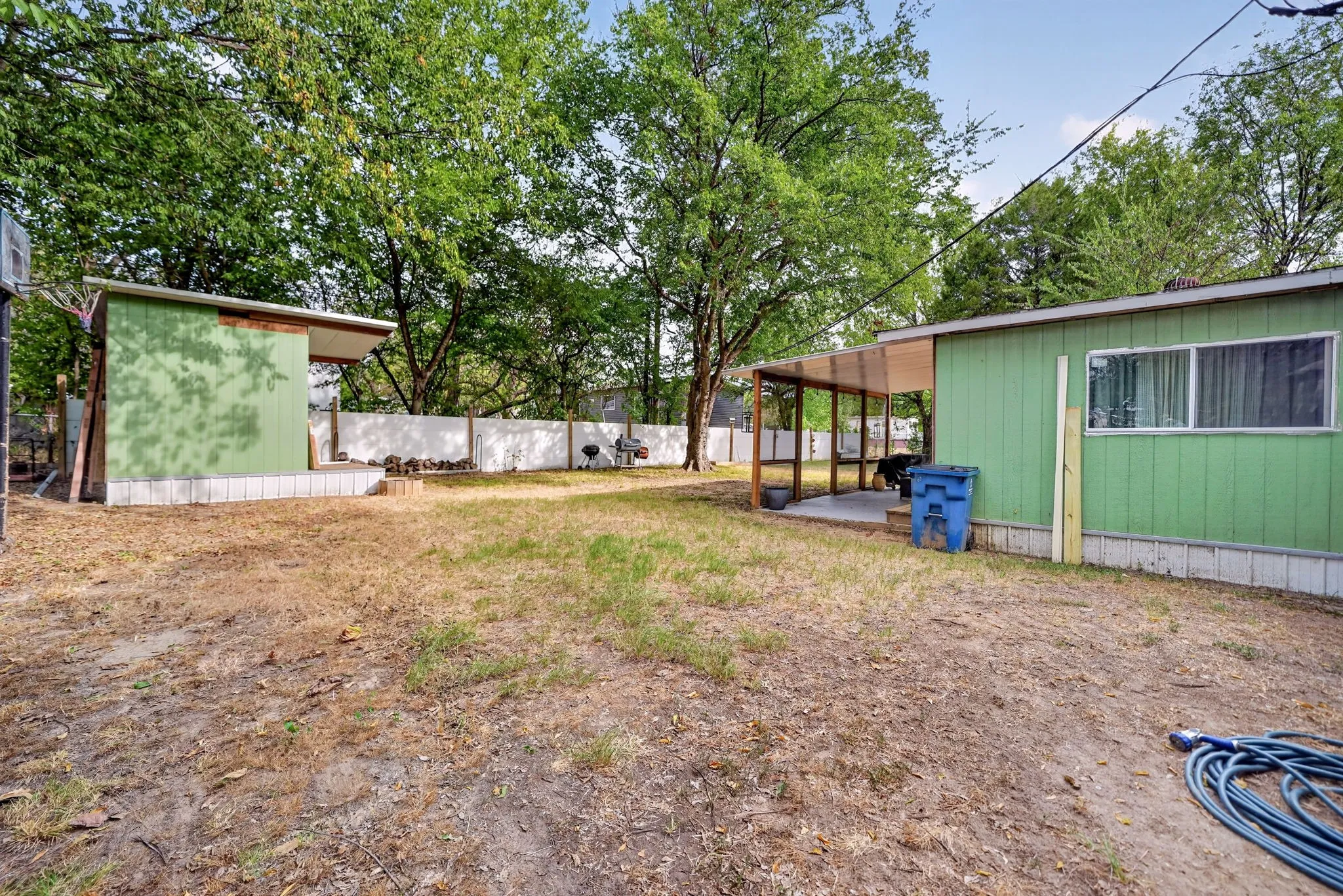 Expansive outdoor space featuring a covered patio, a detached covered structure, and a perimeter fence