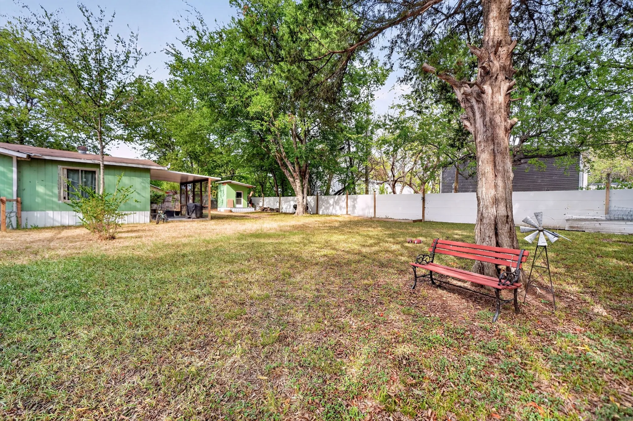 Expansive yard featuring a manicured lawn, established trees, and a privacy fence