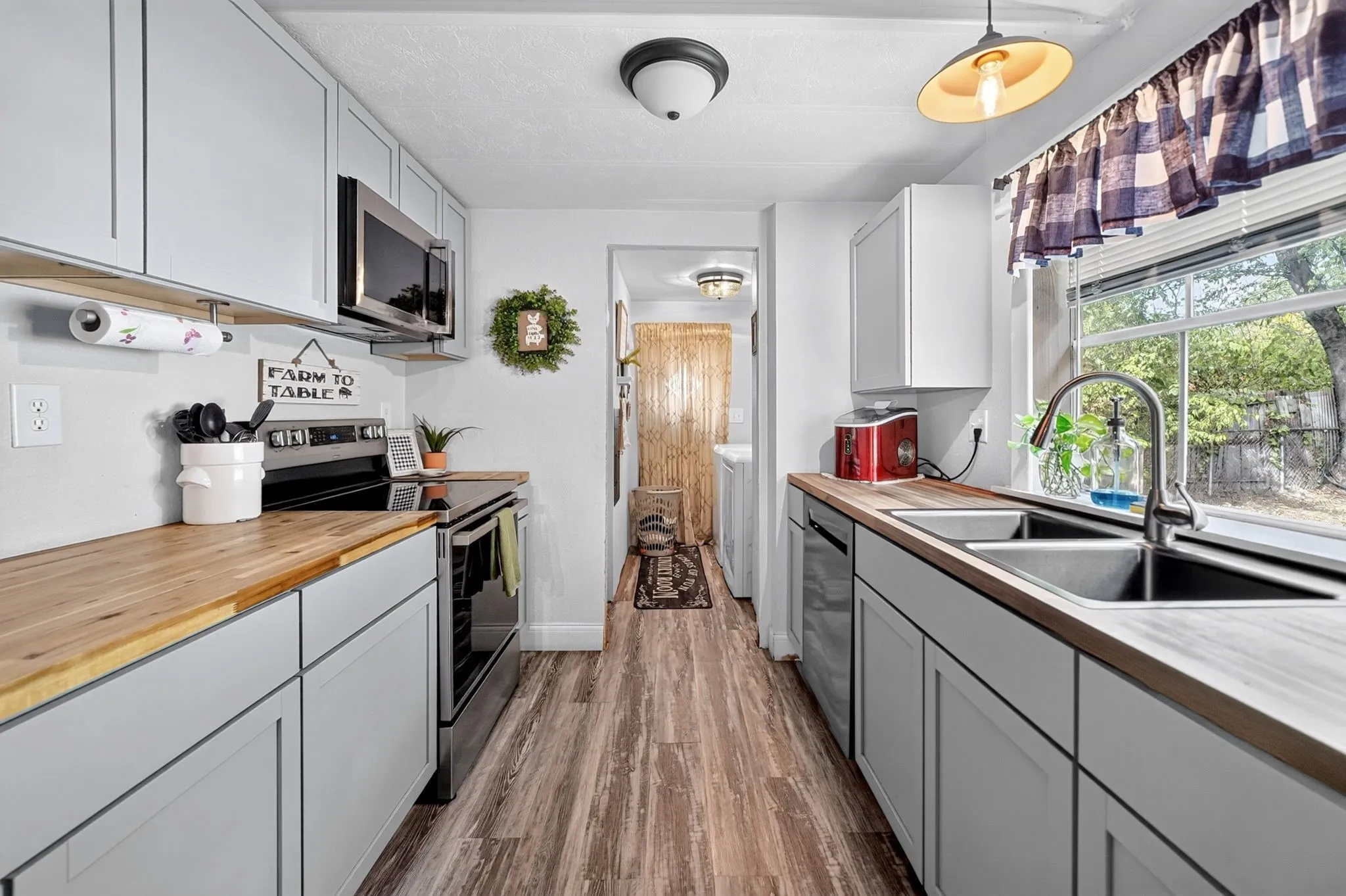 Light gray cabinetry with wood-finish countertops, stainless steel appliances, and wood-finish flooring