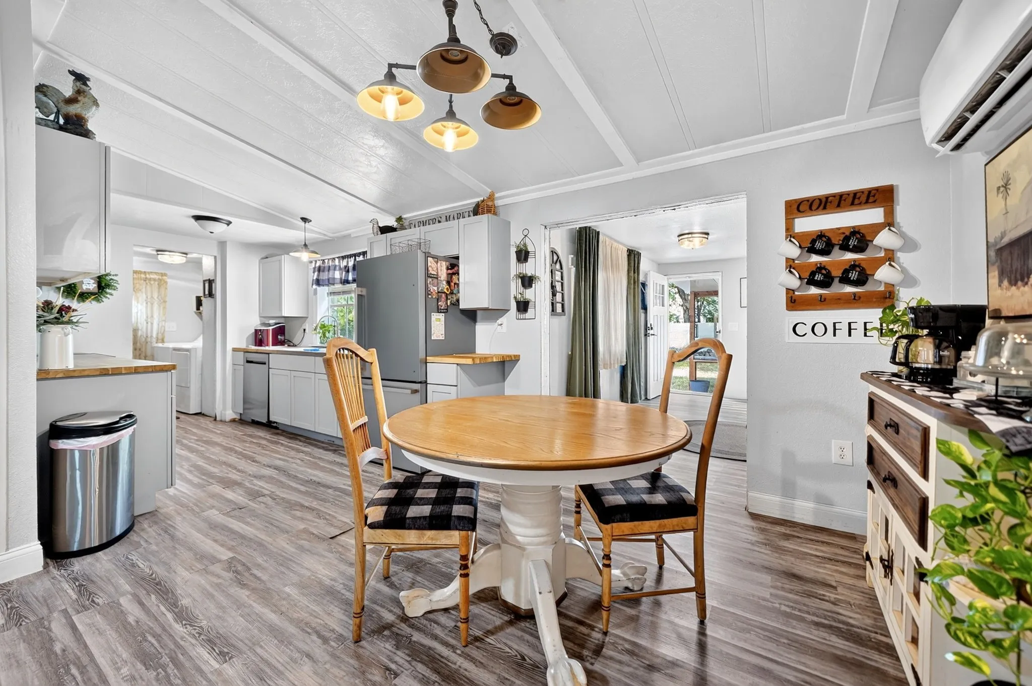 Wood-finish flooring throughout, light gray cabinetry, stainless steel appliances, and a coffered ceiling