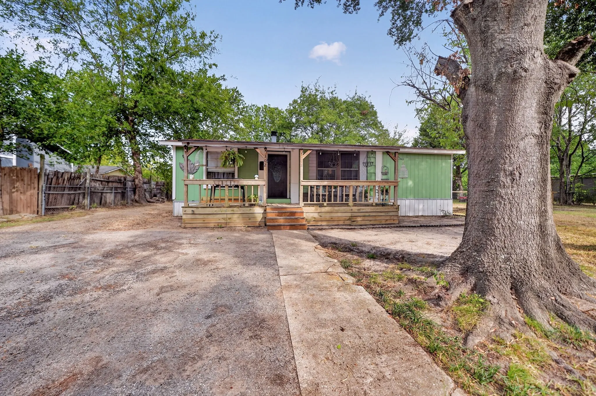 Expansive gravel driveway, wood fencing, and a front porch with wood railing