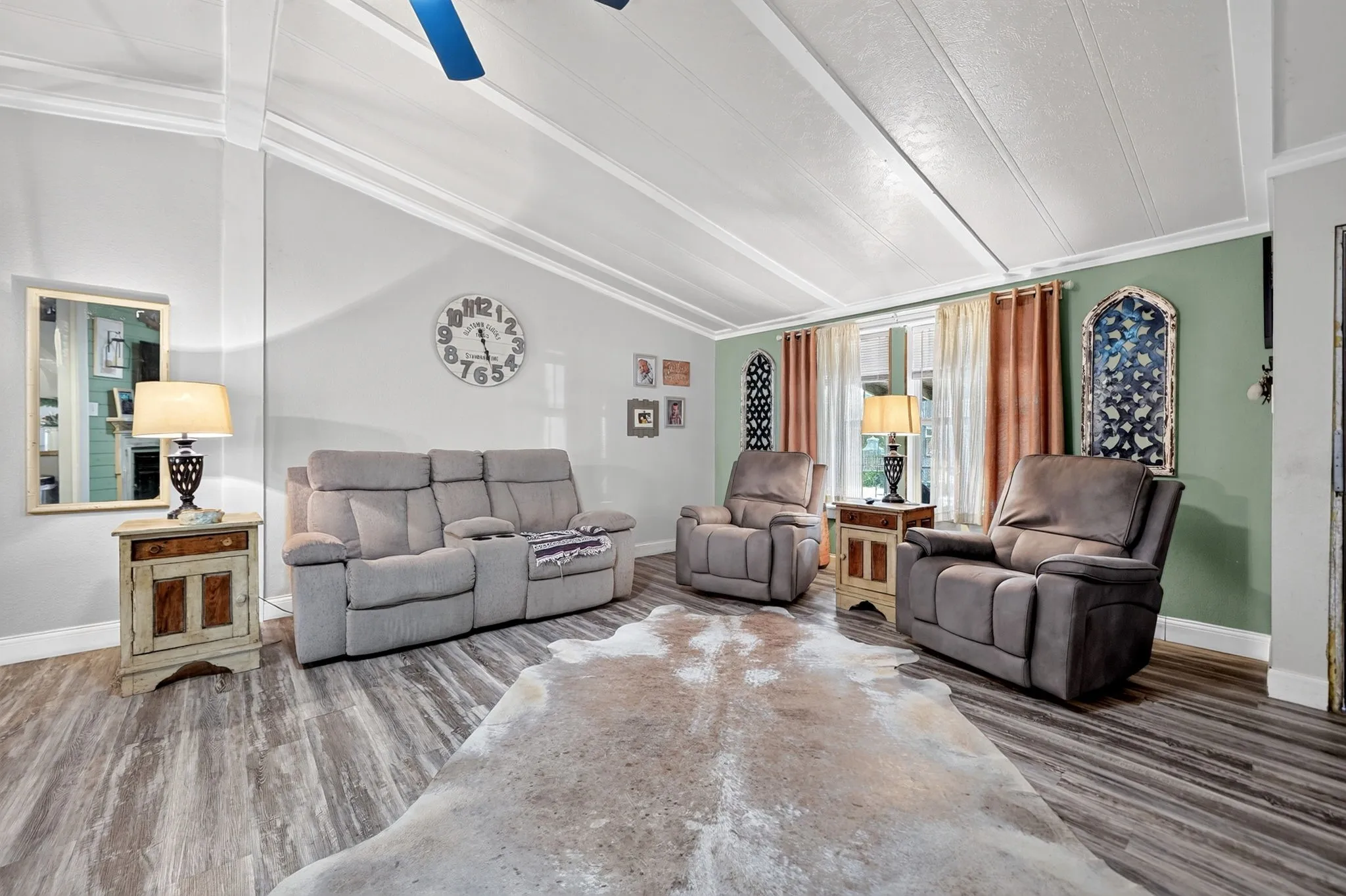 Vaulted ceiling with exposed beams, wood-finish flooring, recessed windows, and a ceiling fan
