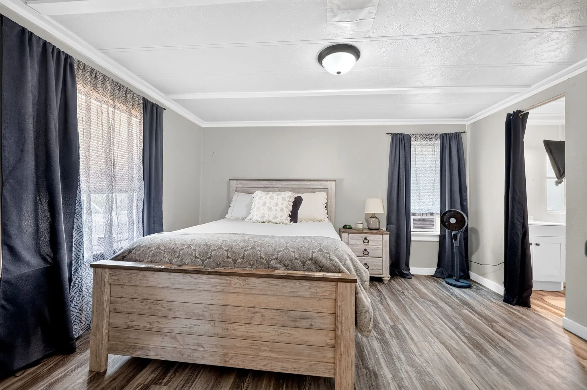 Room featuring wood-finish flooring, a ceiling-mounted light fixture, and crown molding