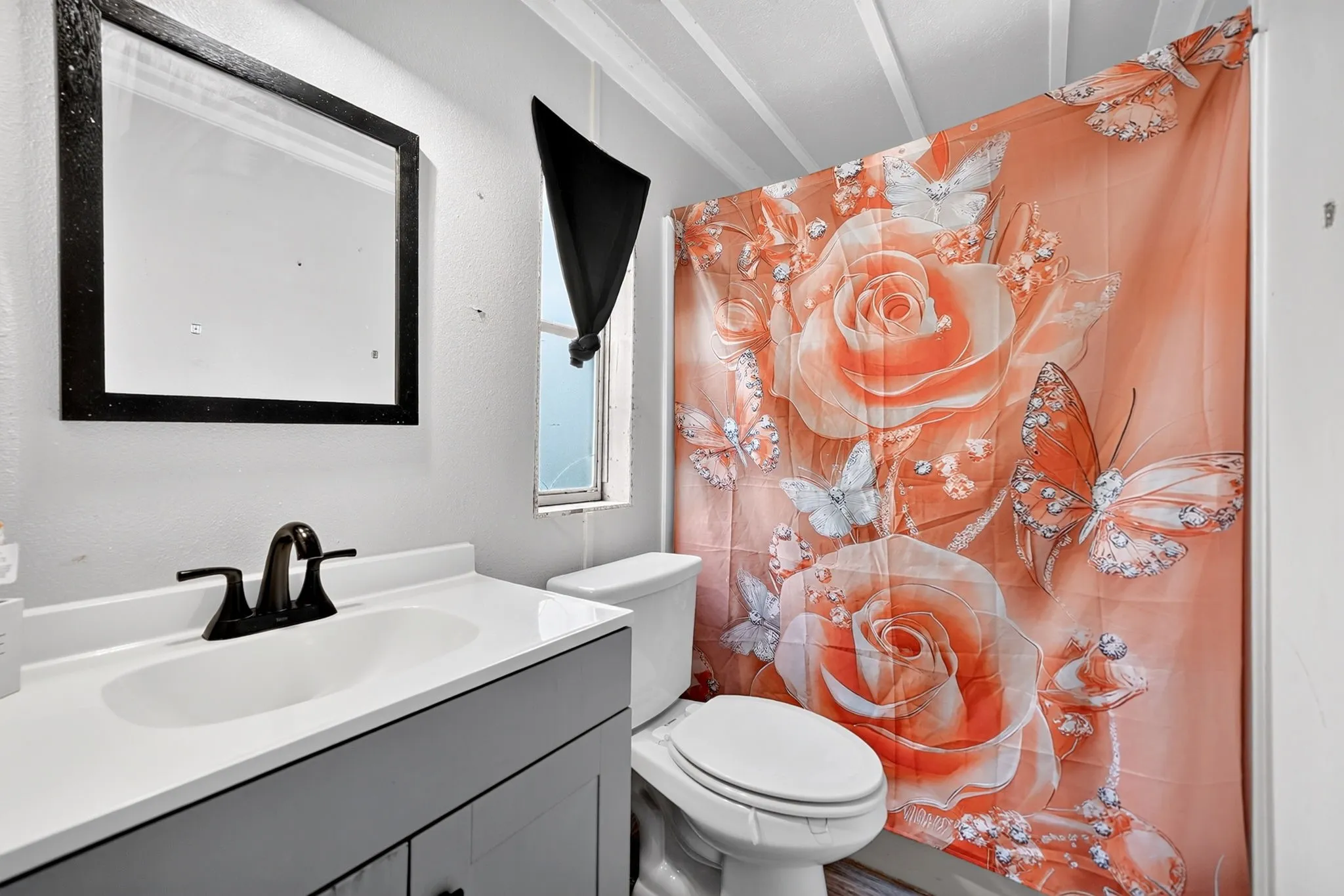 Vanity with integrated sink, black-finish faucet, and coordinating framed mirror