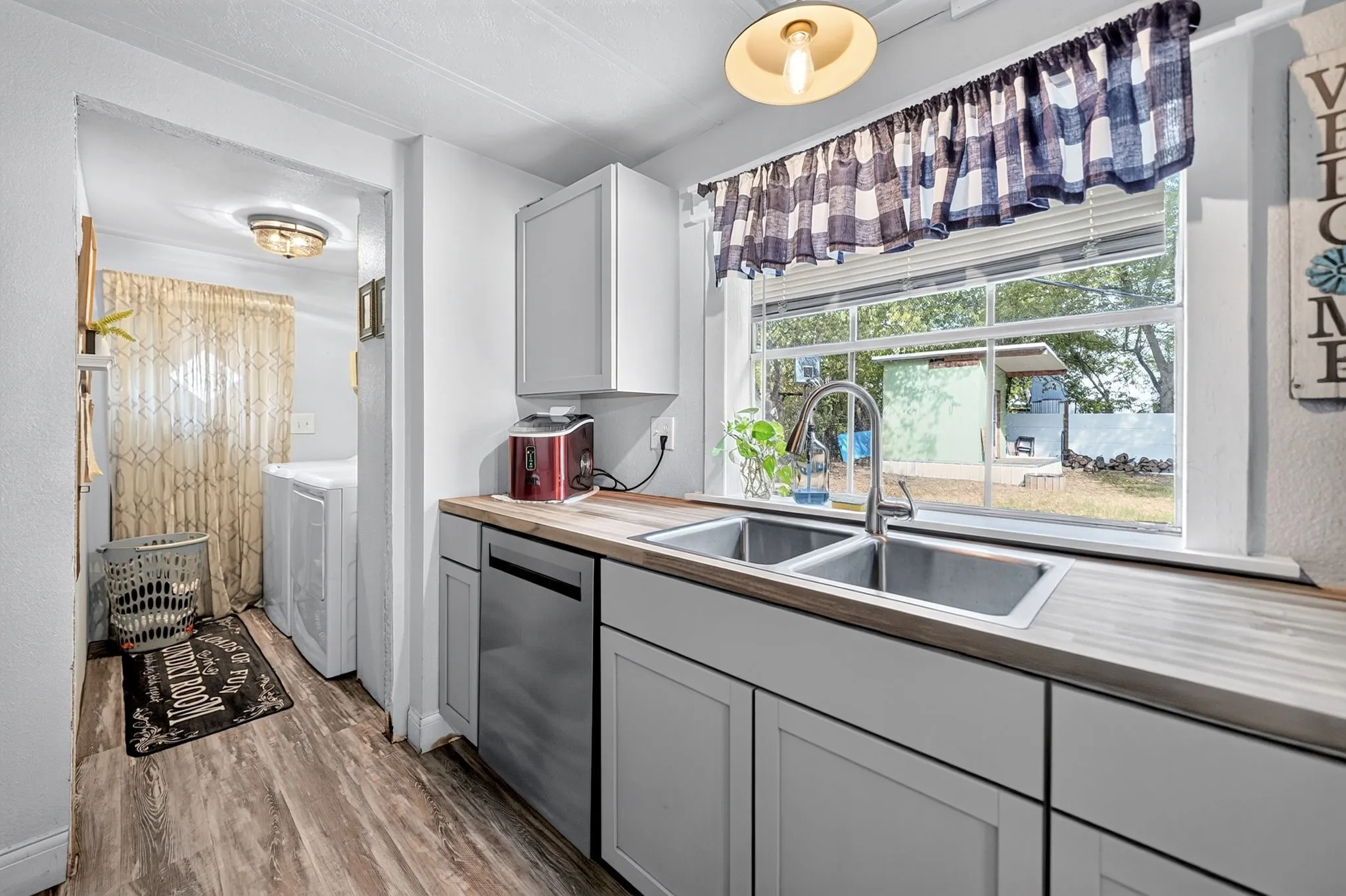 Dual basin stainless steel sink with a high-arc faucet, wood-finish countertops, and light gray cabinetry
