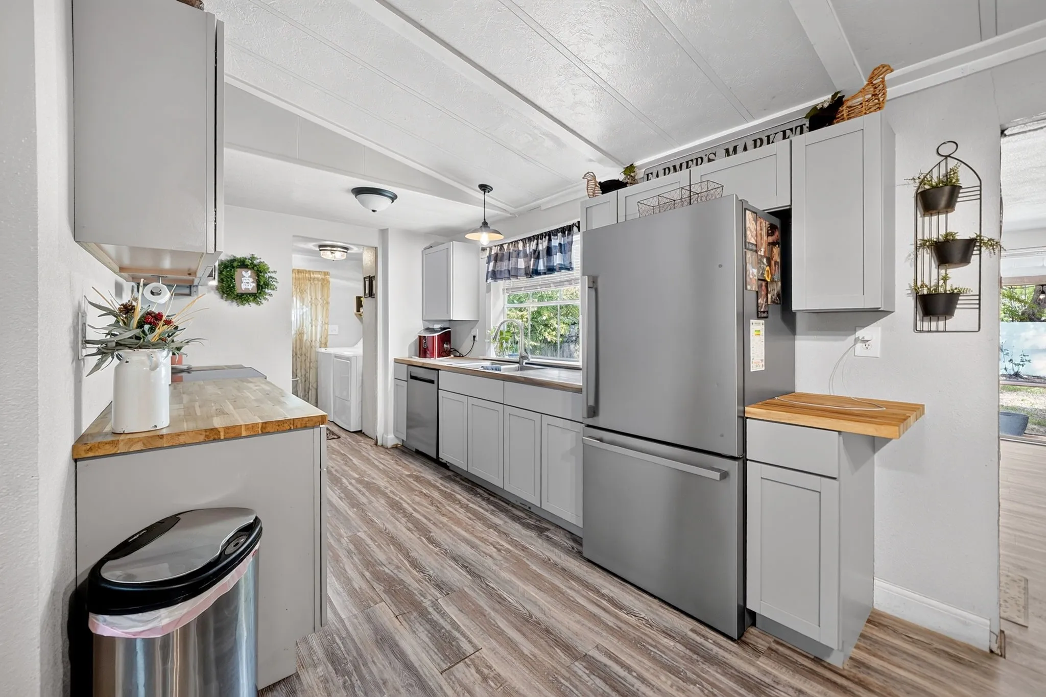 Kitchen featuring light gray cabinetry, wood-finish countertops, stainless steel appliances, and wood-finish flooring