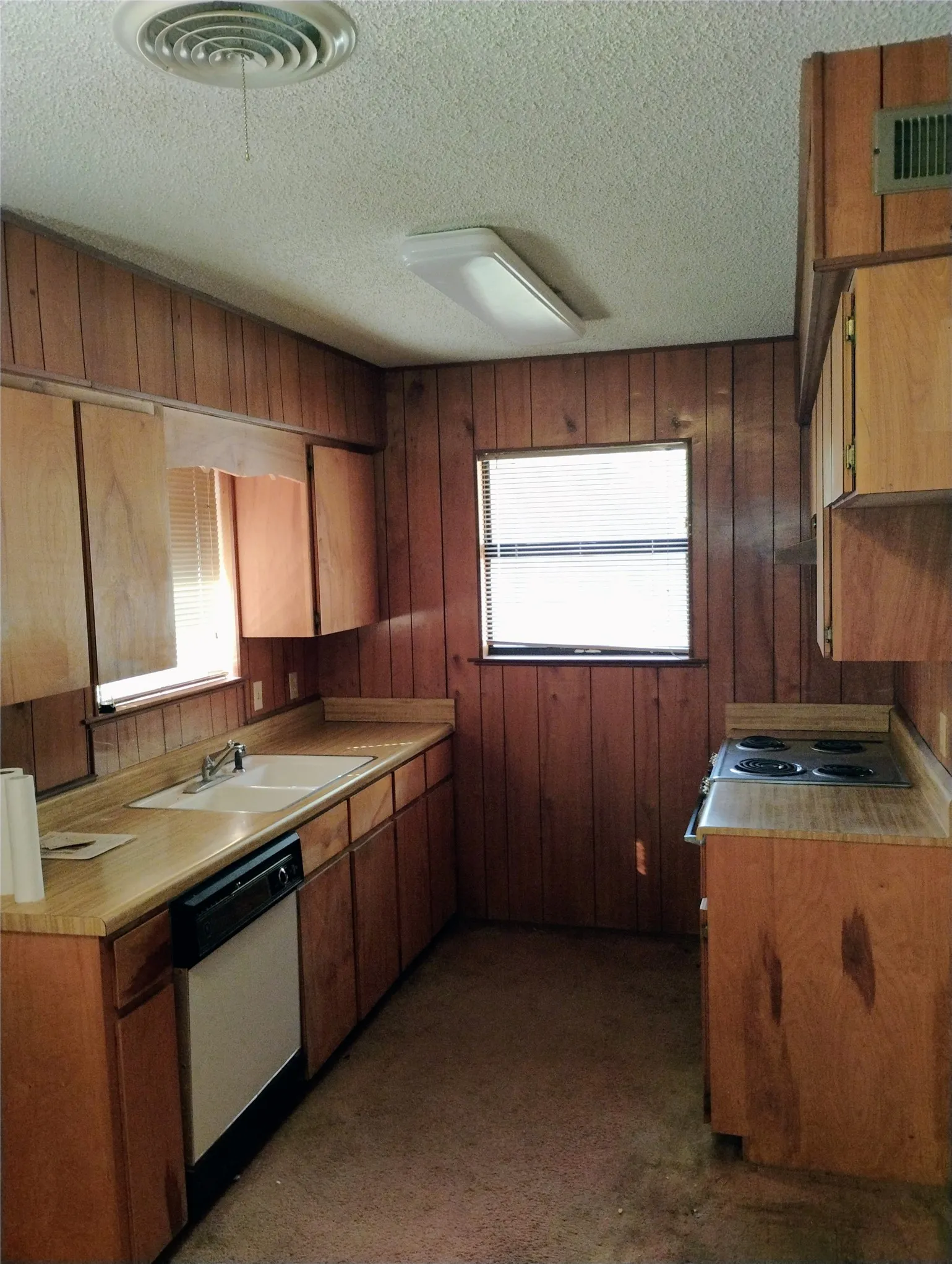 Kitchen featuring wood paneling,cabinetry, built-in sink, and built-in stovetop