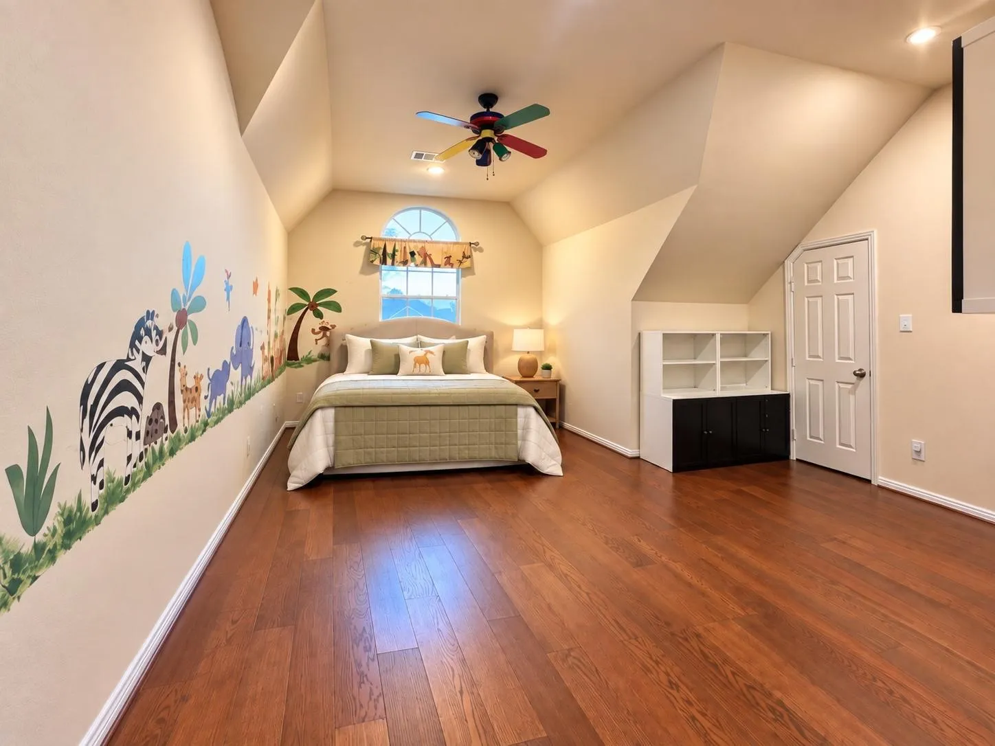 Wood-finish flooring, vaulted ceilings, arched window, built-in shelving, and a ceiling fan