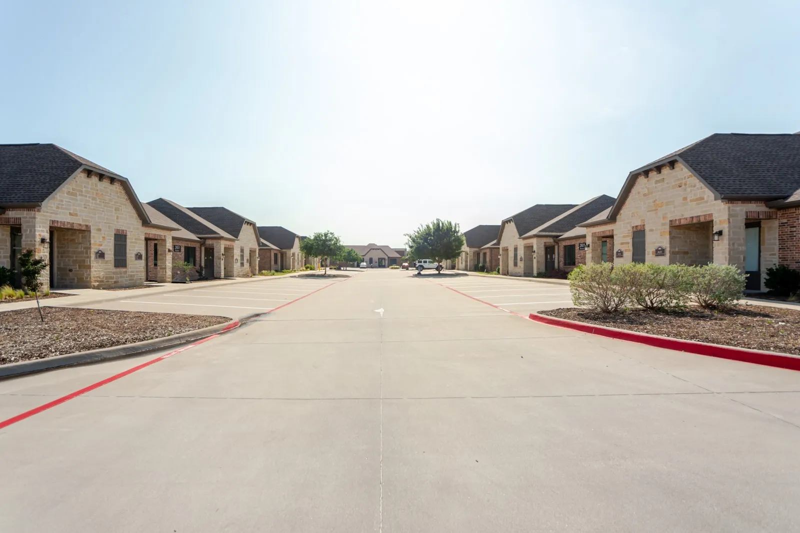 Stone veneer exteriors with dark shingle roofs, concrete parking areas, and planted landscaping
