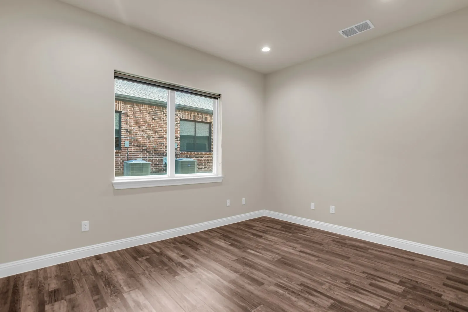 Wood-finish flooring, recessed lighting, and a single window with white trim