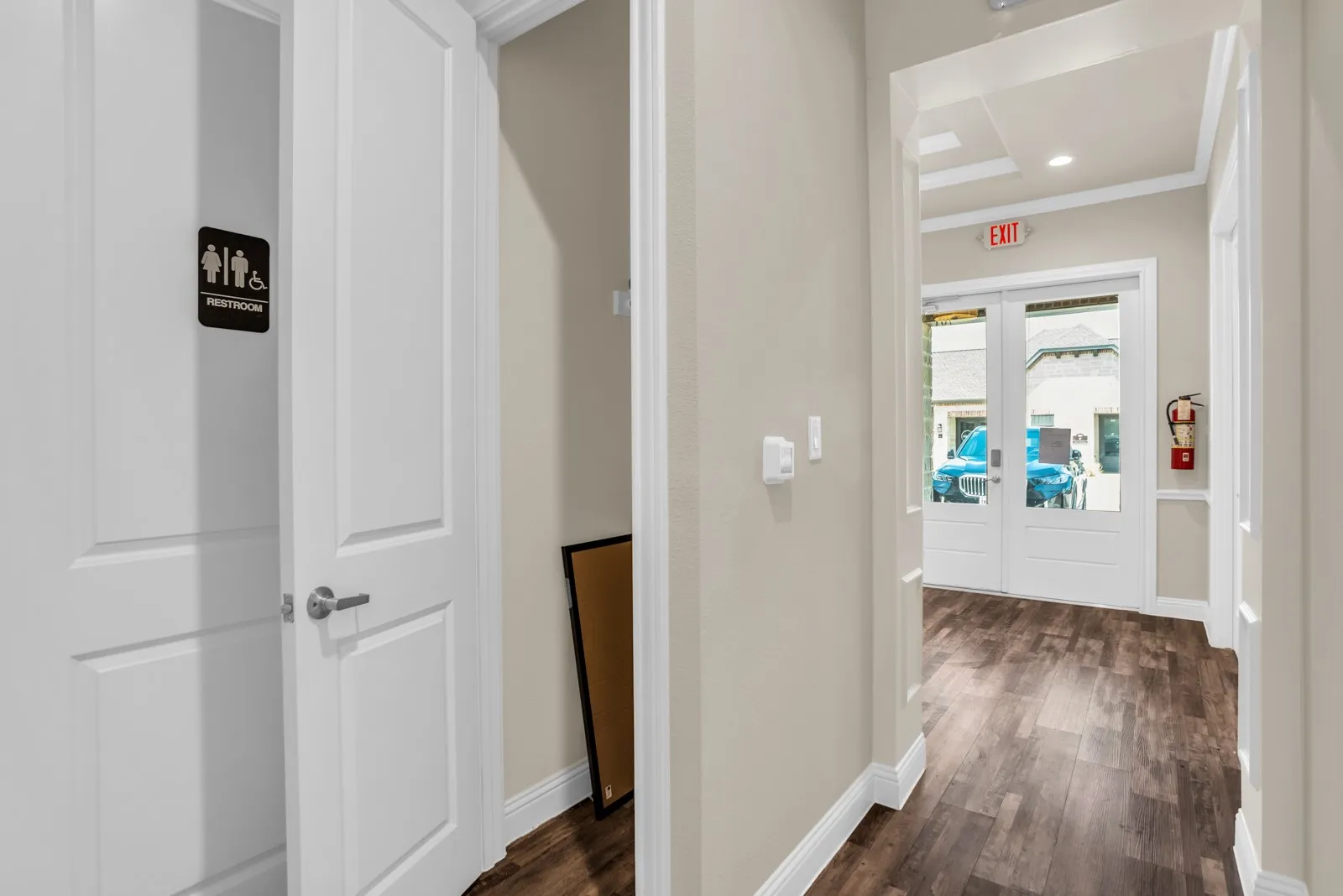 Wood-finish flooring, light-toned walls, white trim, recessed lighting, and double glass-paneled doors