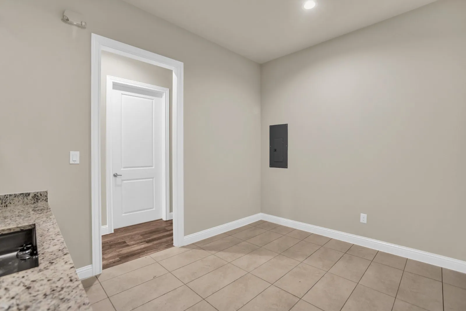 Recessed lighting, tile flooring, granite countertop, stainless steel sink, and white trim