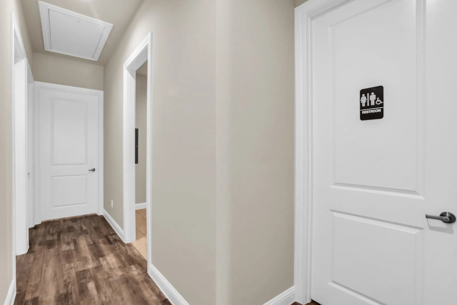 Hallway featuring wood-finish flooring, light neutral wall paint, and white trim