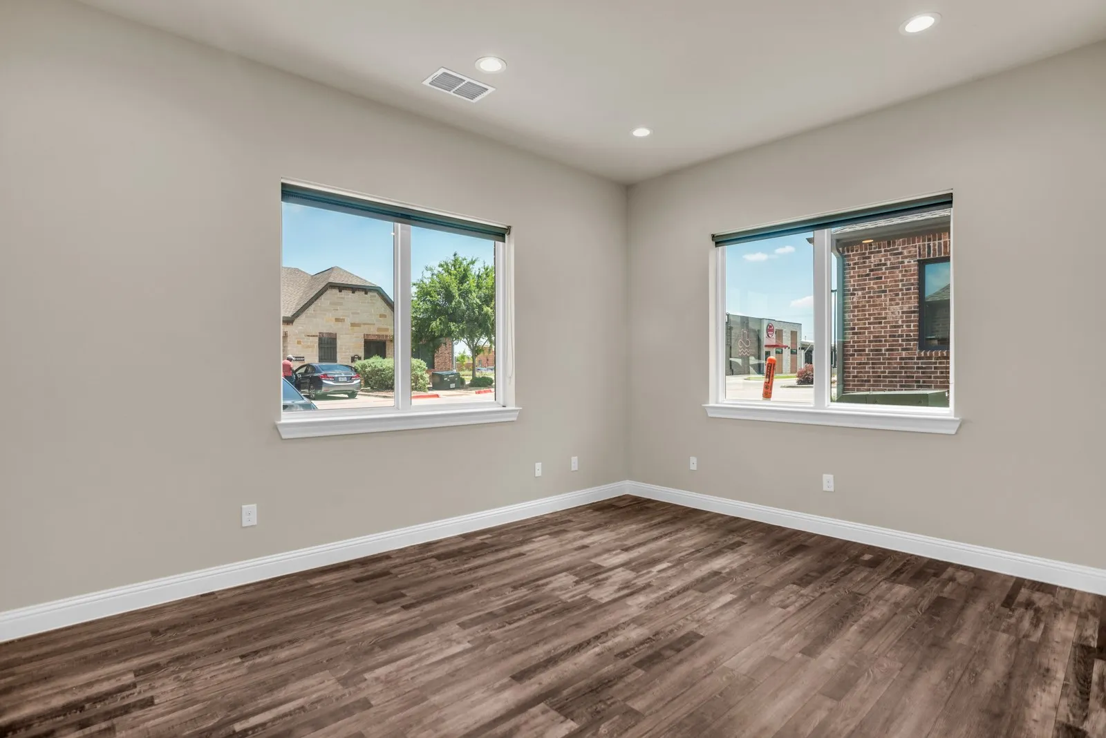 Wood-finish flooring, recessed lighting, and multiple windows with white trim