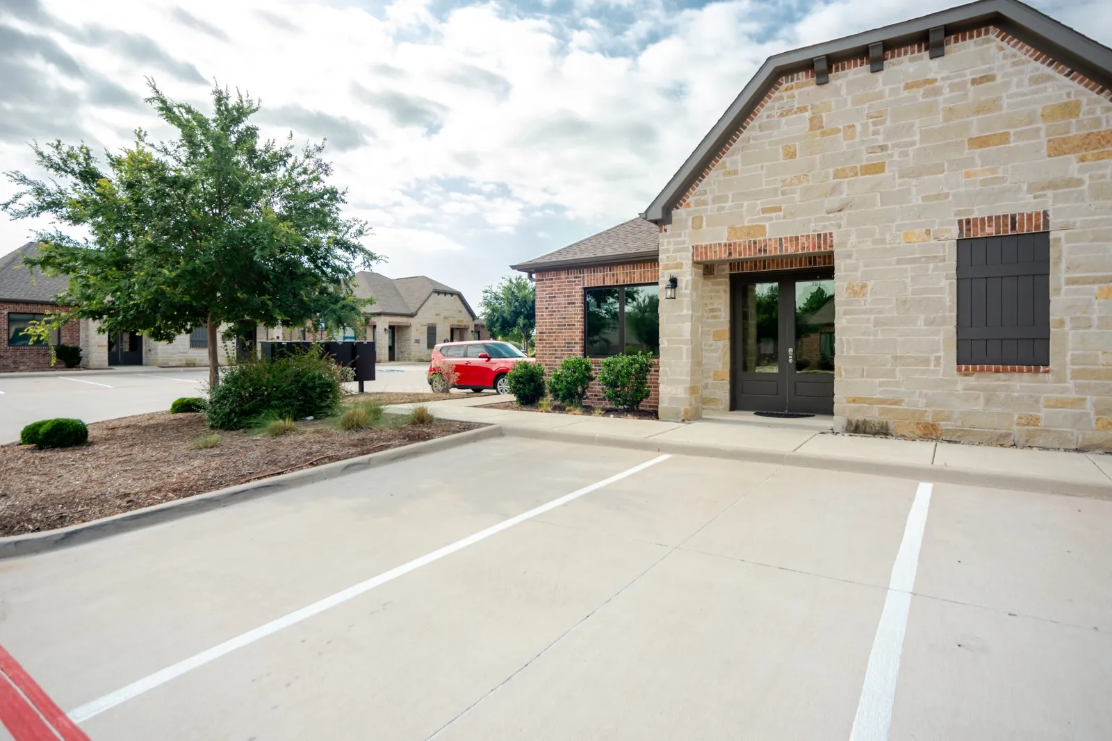 Stone facade building with a dark double-door entry, exterior lighting, and dark window shutters