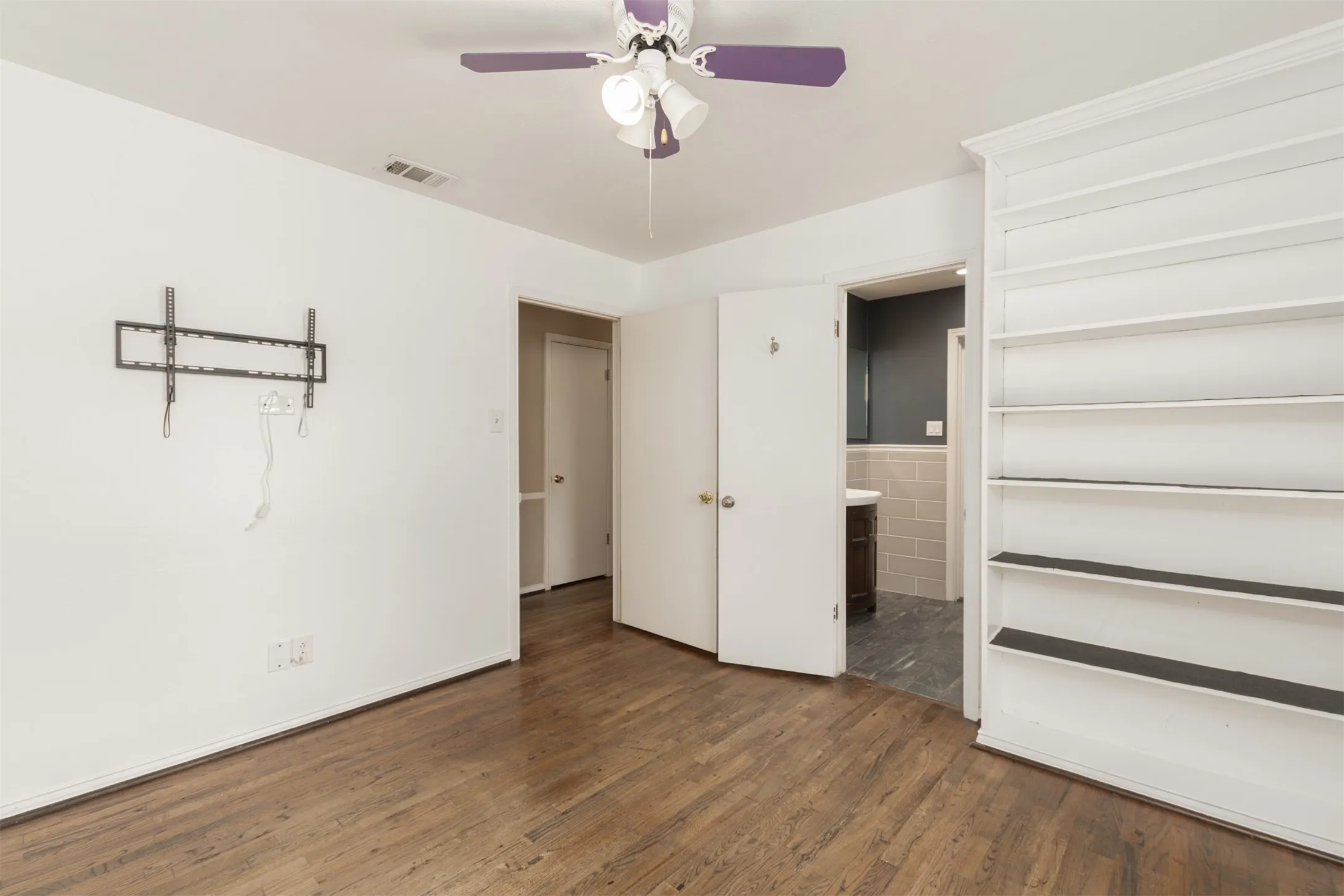 Wood-finish flooring throughout, white walls, and a ceiling fan with light fixture