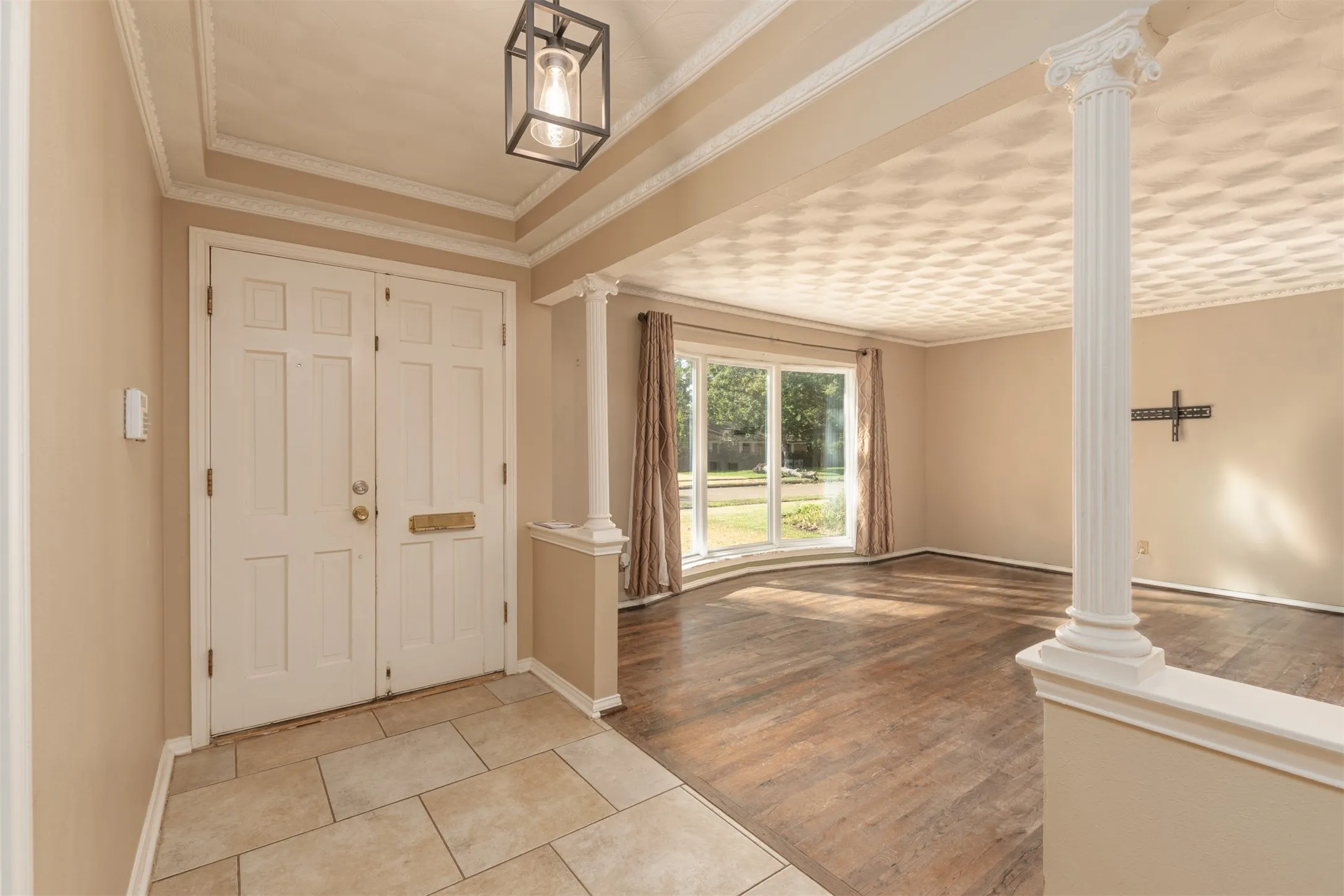 Double entry doors with panel details, tile flooring, fluted column, bay window, and a coffered ceiling