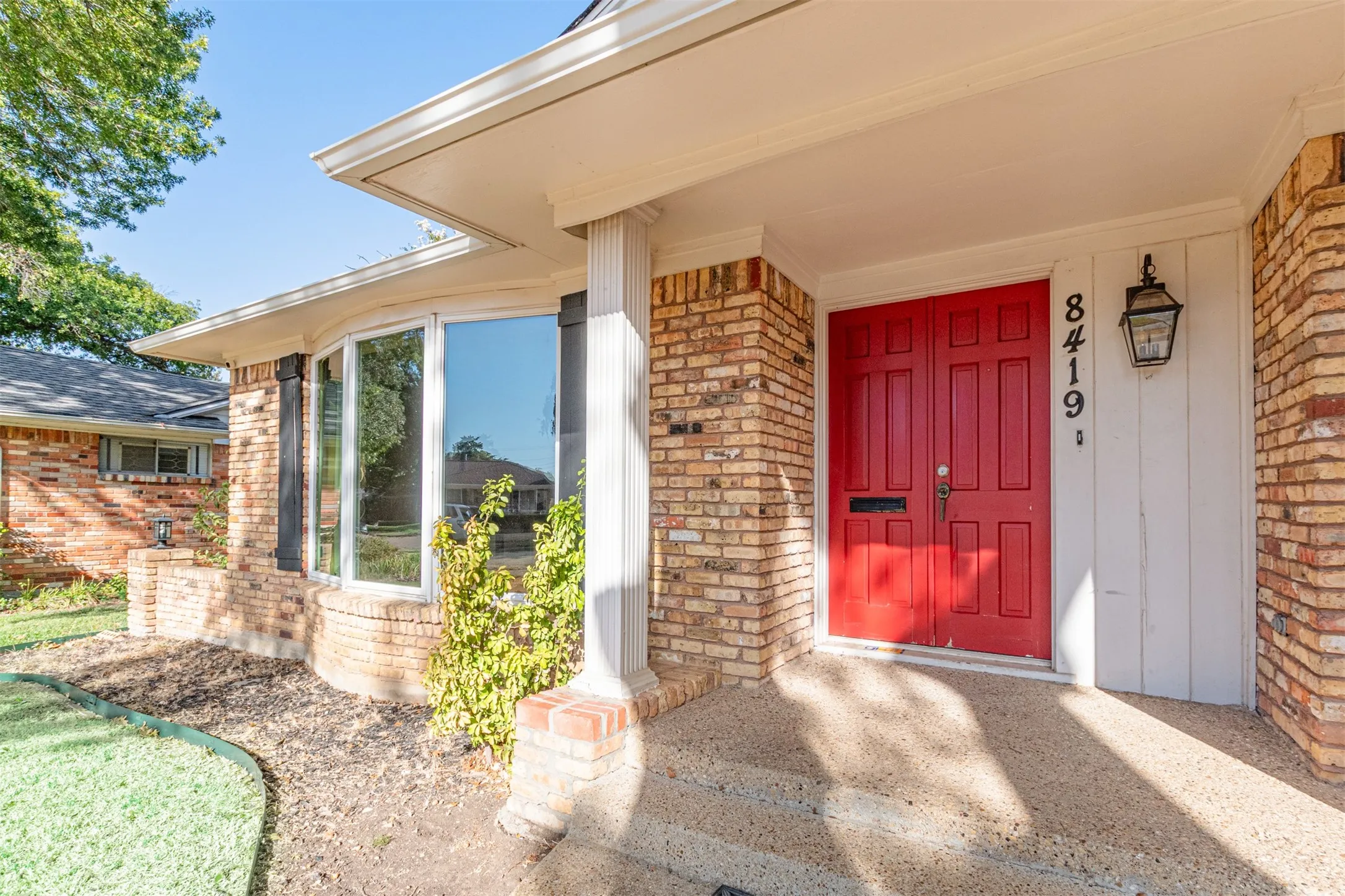 Brick exterior with a prominent red double door entry, featuring a traditional lantern-style light fixture