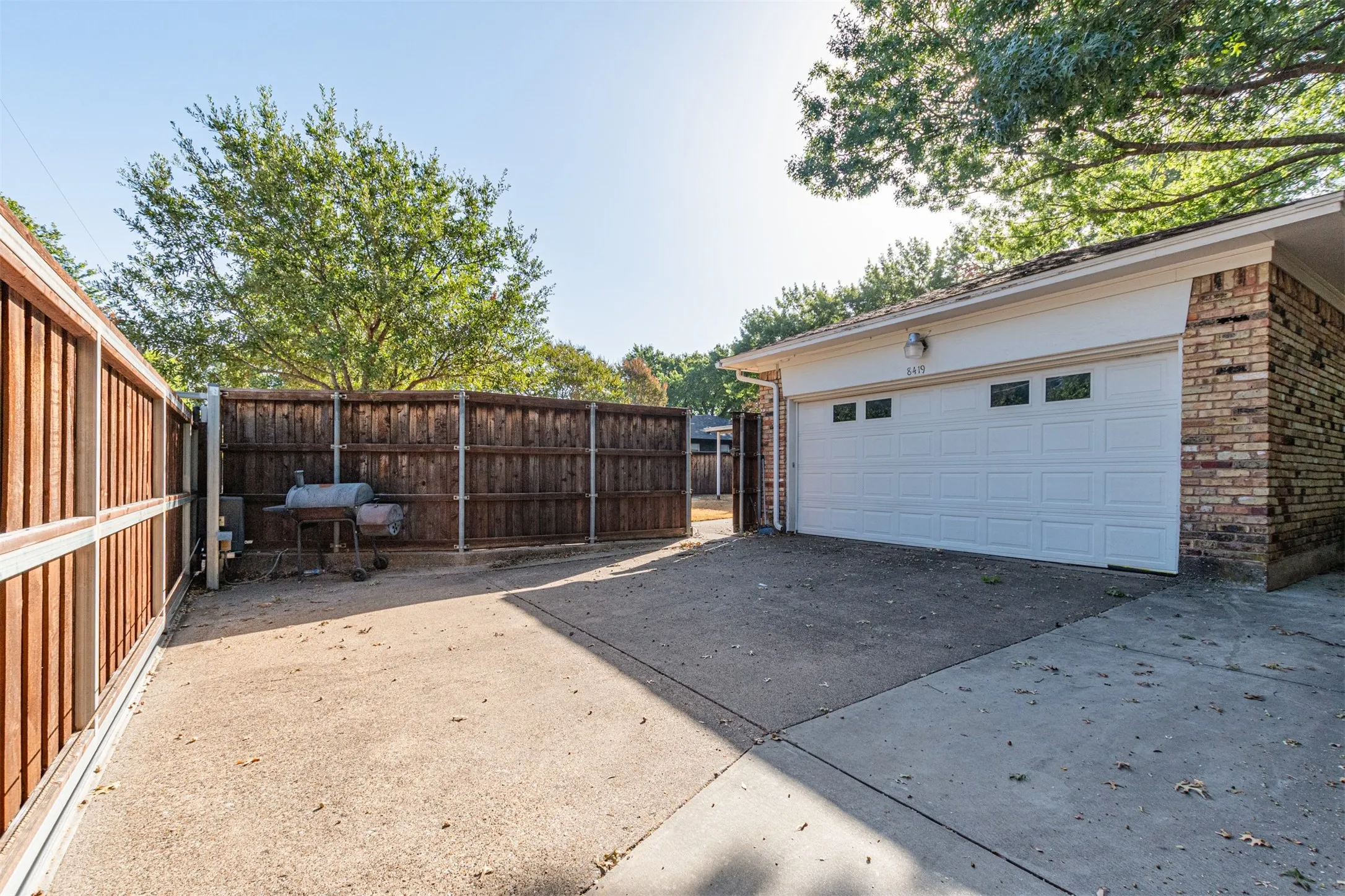 Detached garage with a paneled door and window inserts, brick exterior, and a concrete driveway