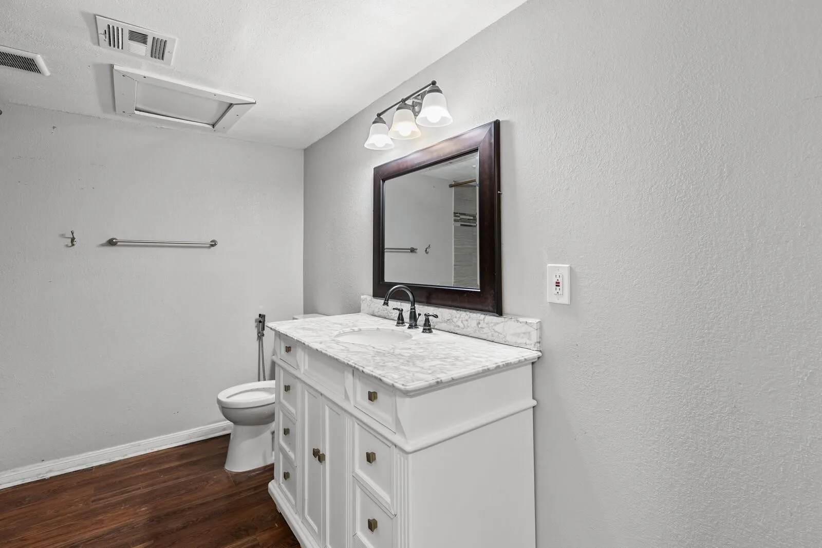 White vanity with multiple storage drawers and cabinet doors, a light-colored countertop, and a dark-framed mirror