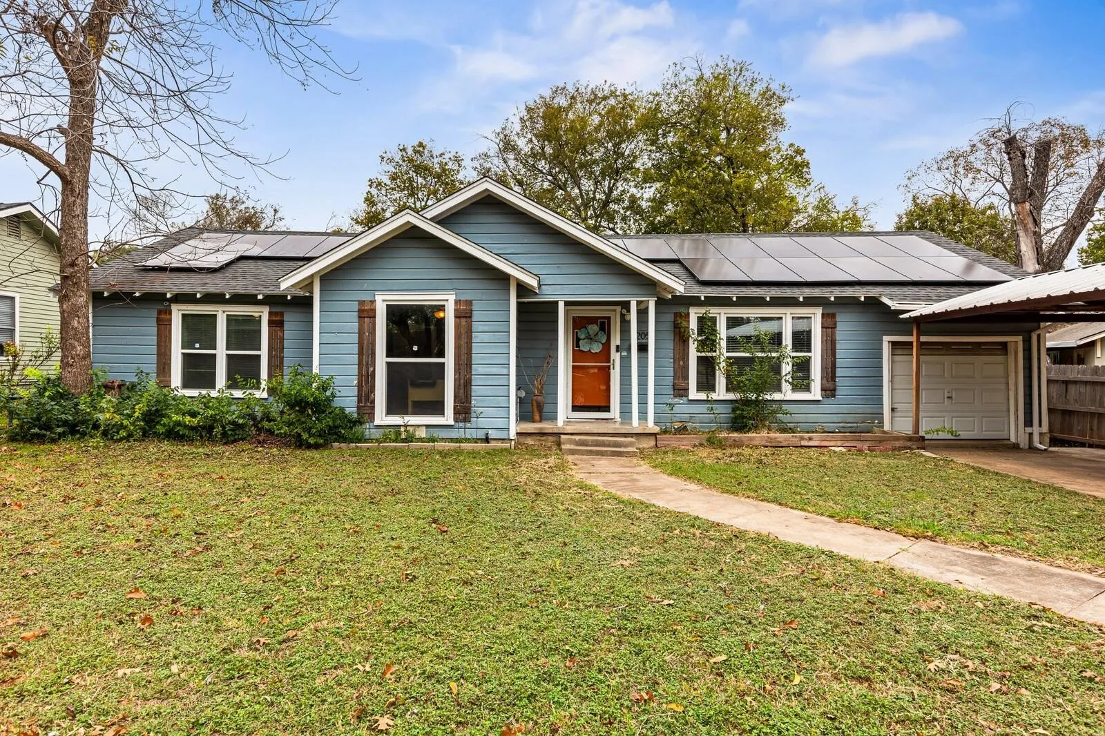 Light blue siding exterior with white trim, a covered carport, and solar panels on the roof