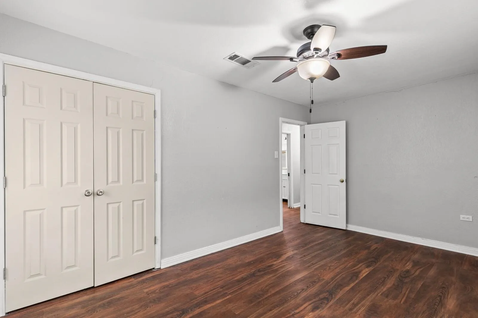 Wood-finish flooring with a ceiling fan and light fixture