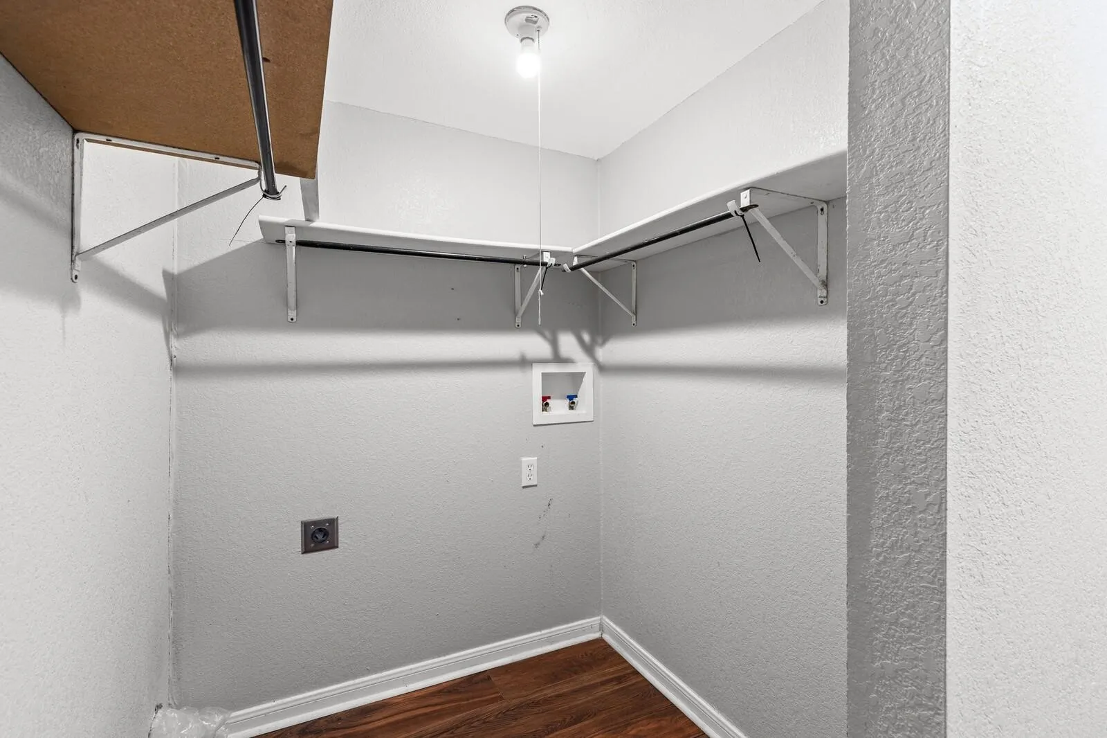 Utility area with wood-finish flooring, built-in shelving, a clothes rod, and appliance hookups