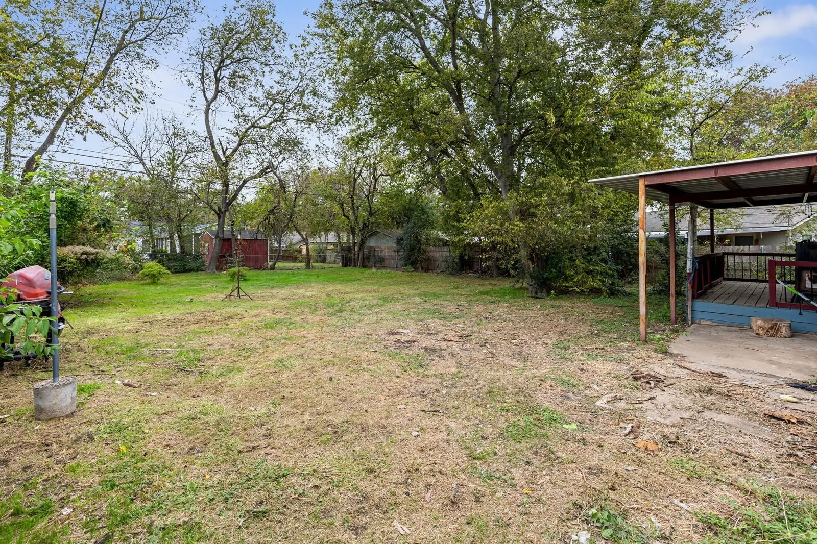 Expansive yard space featuring mature trees and a covered patio with a wood-plank deck