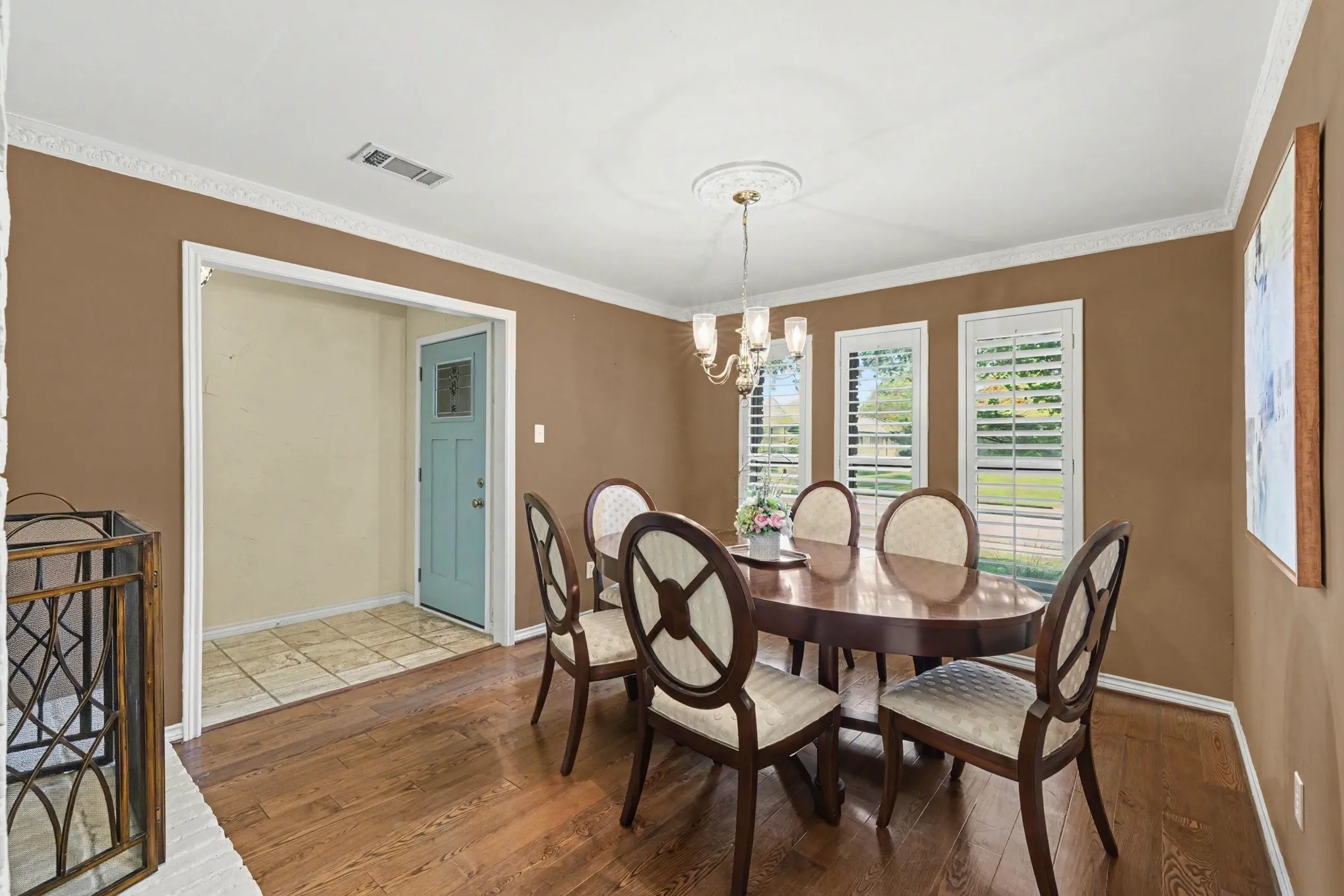 Hardwood flooring, crown molding, and a chandelier with a ceiling medallion