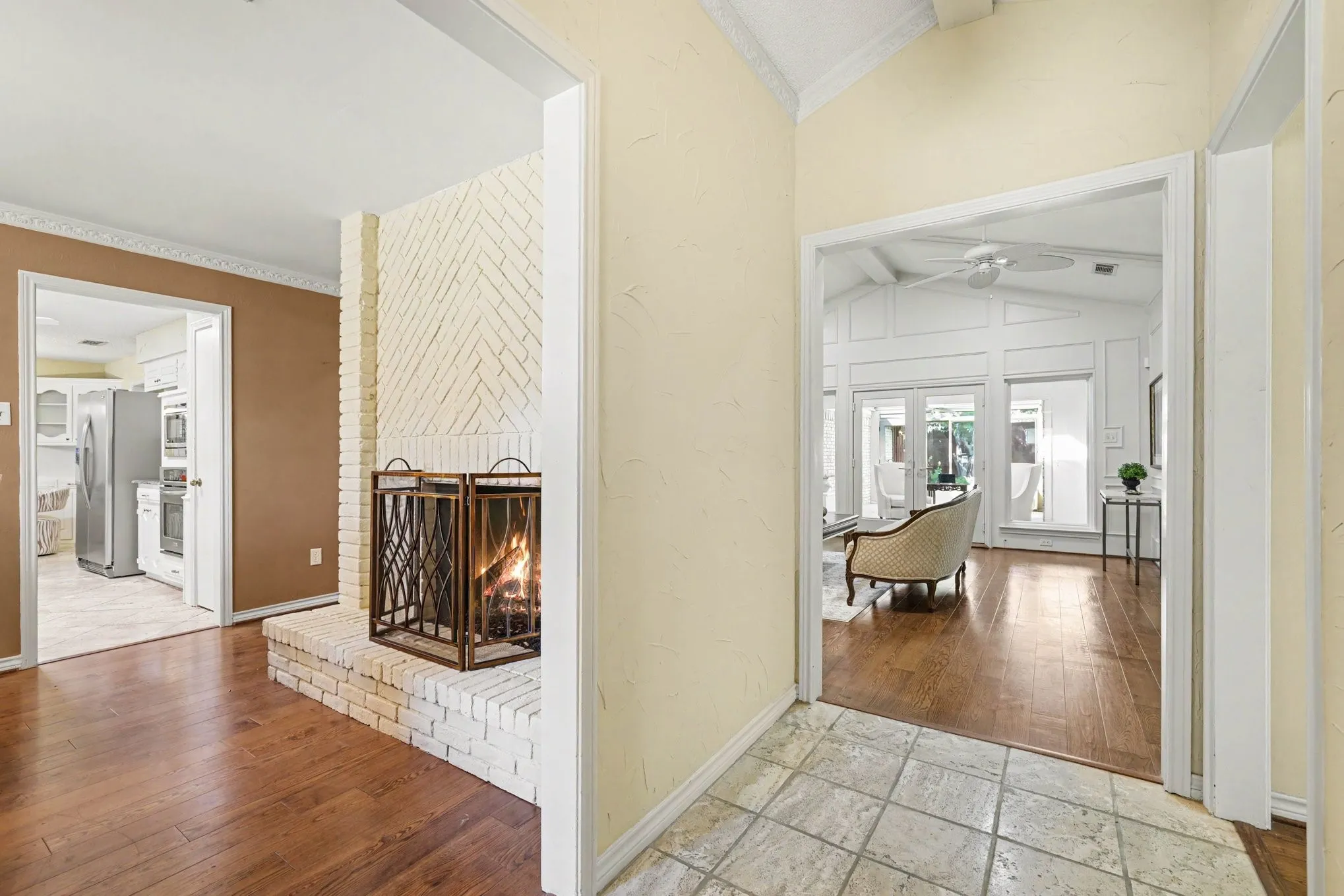 White brick fireplace with an elevated hearth, wood-finish flooring, and vaulted ceilings