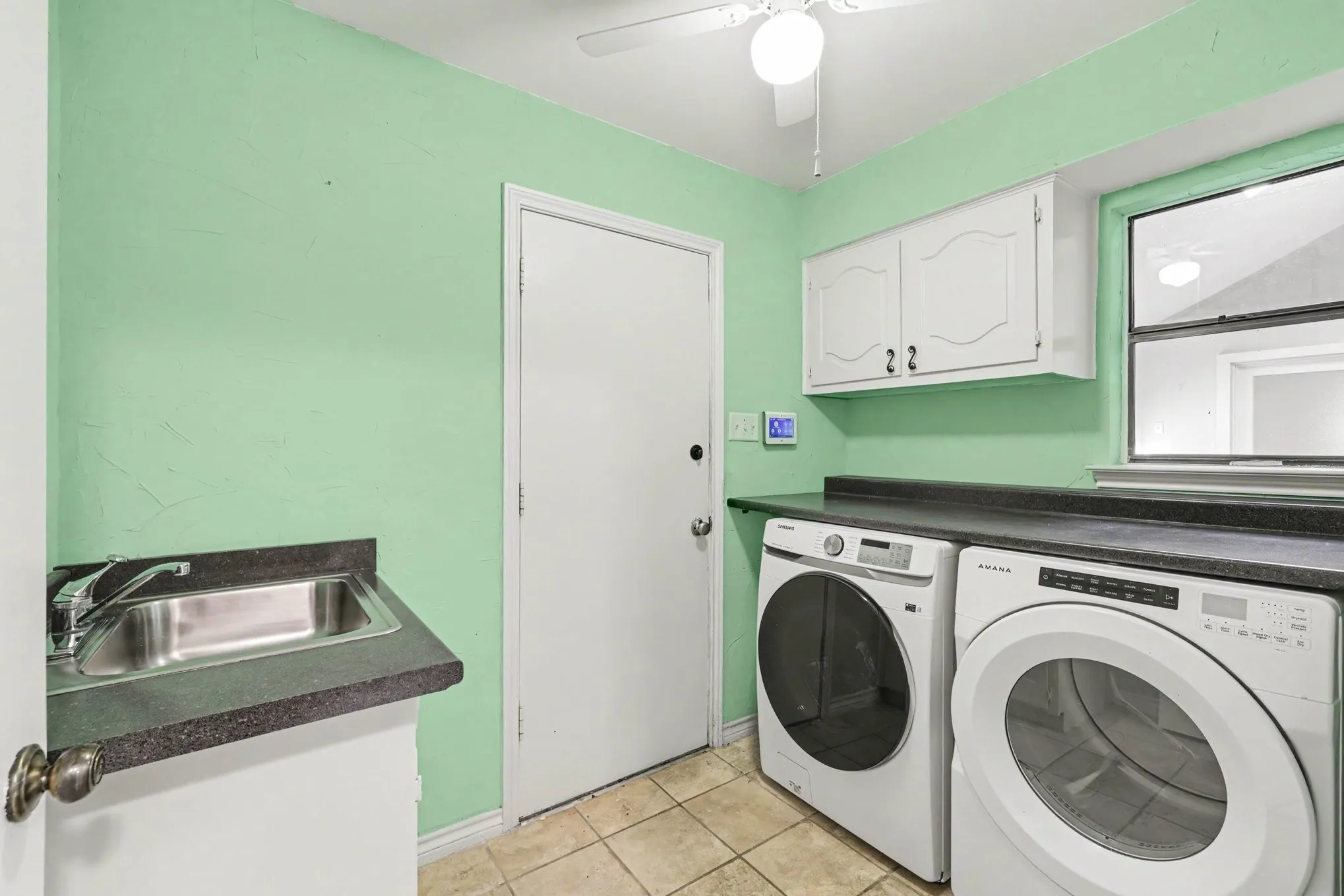 Utility area with built-in sink, dark countertop space, upper cabinetry, and tile flooring