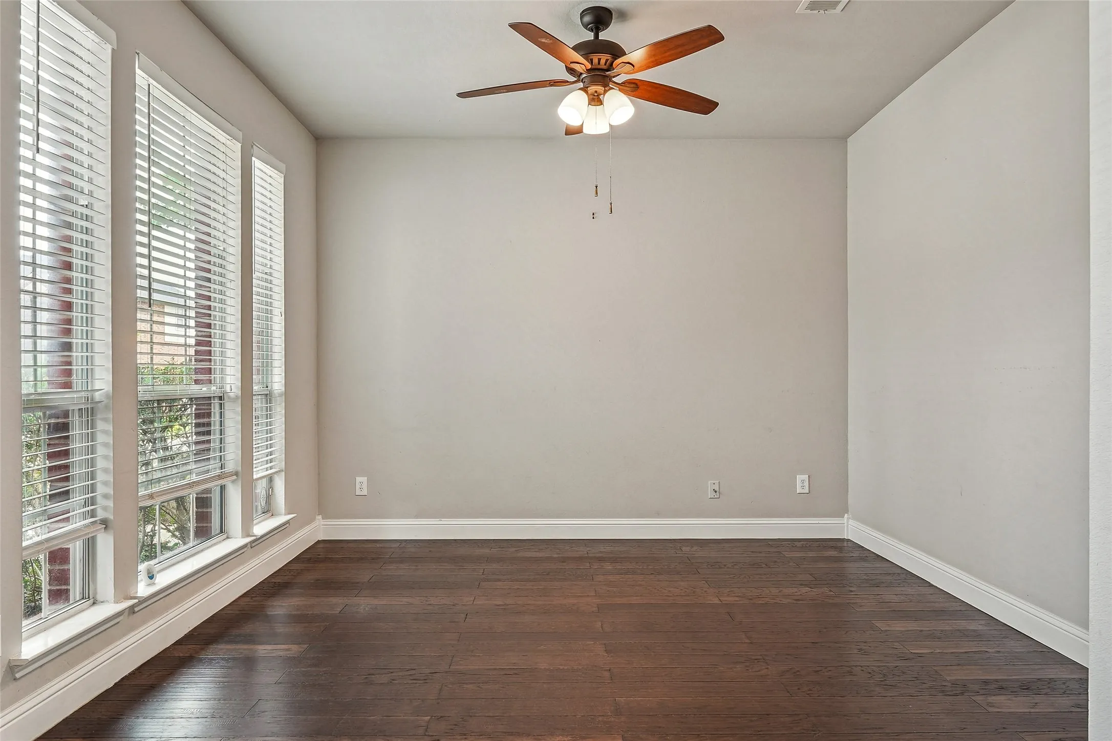 Empty room with dark wood-type flooring and a ceiling fan