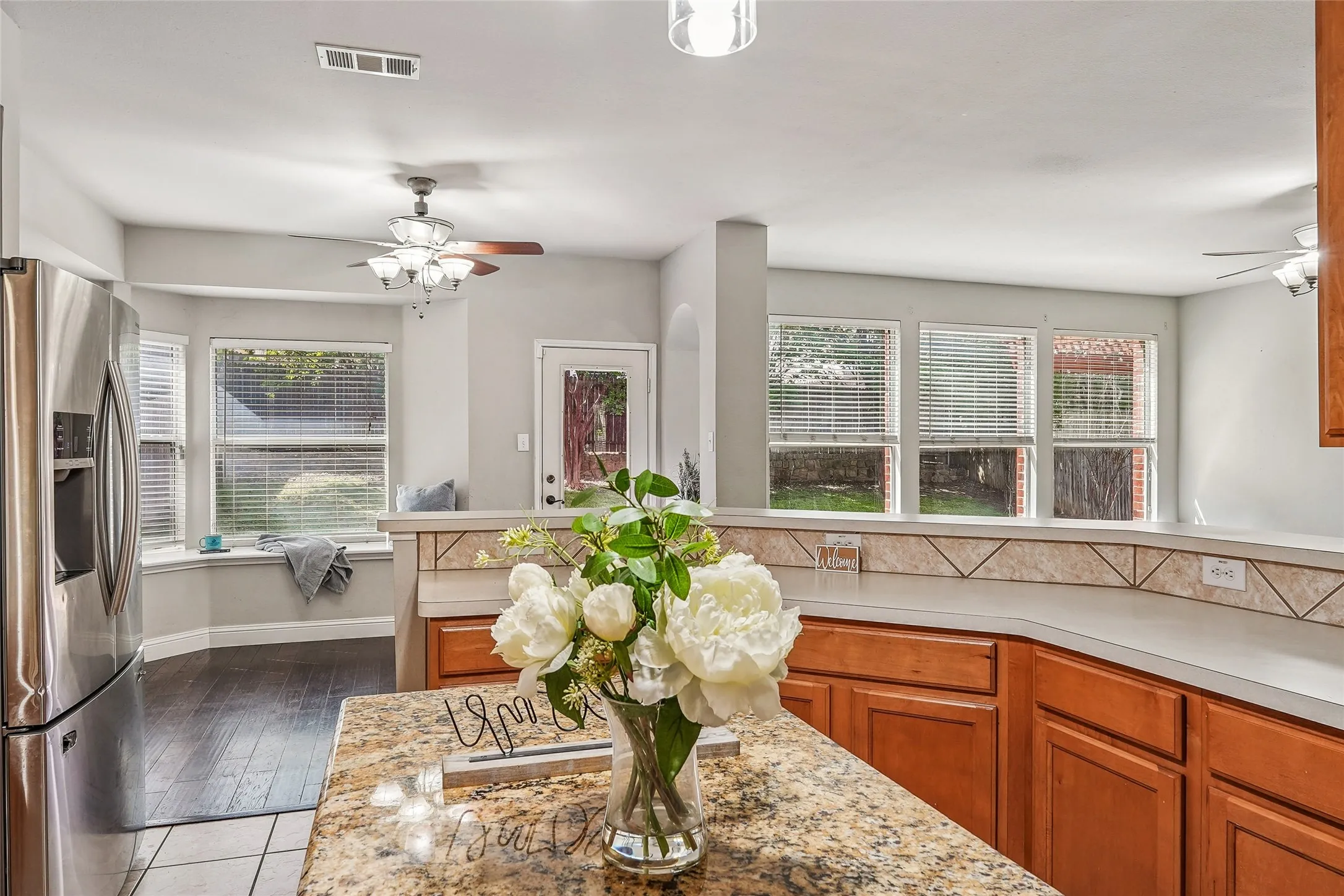 Kitchen with a ceiling fan, stainless steel fridge with ice dispenser, and wood finish cabinetry