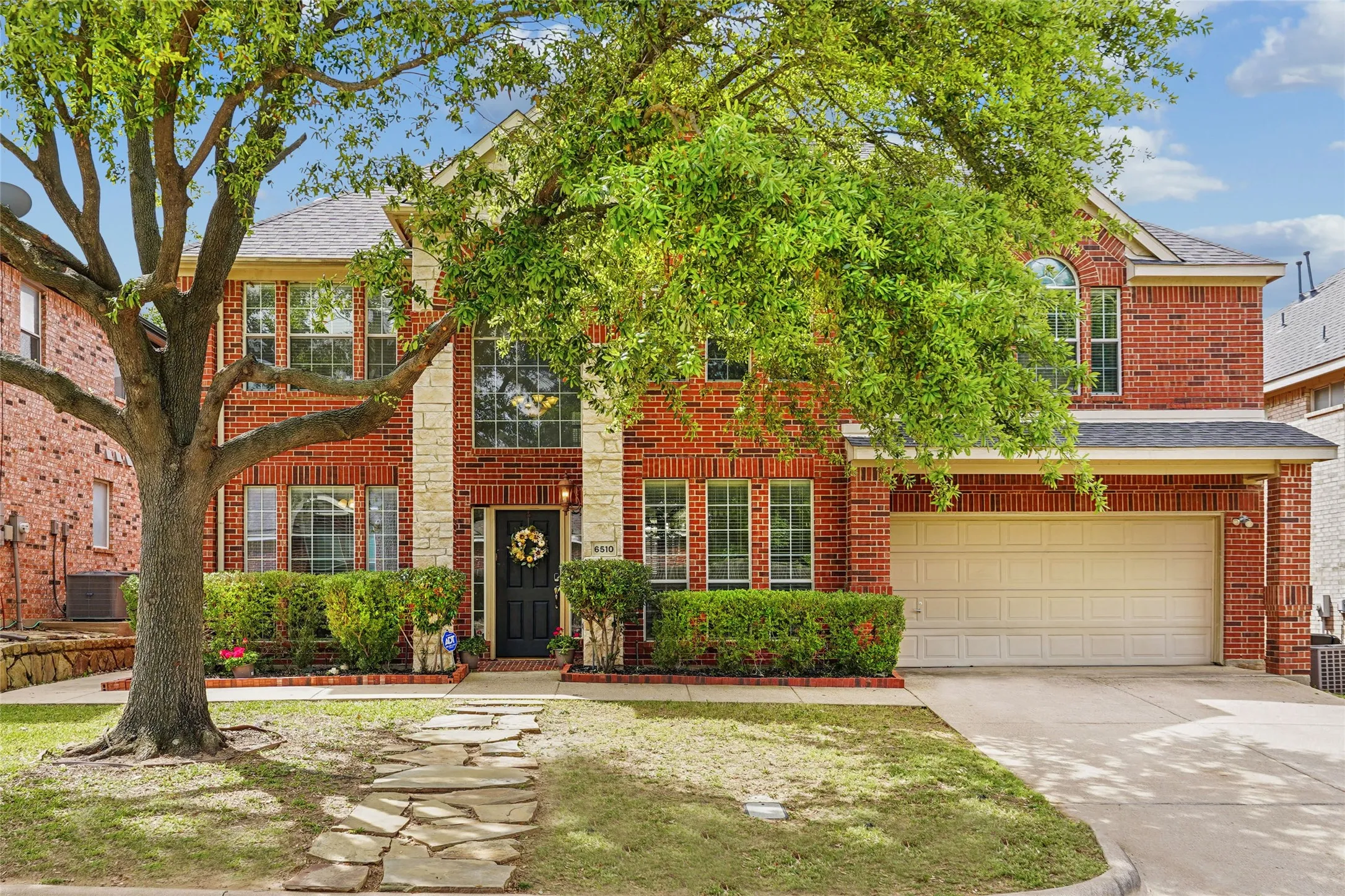 Traditional-style house featuring driveway, an attached garage, brick siding, roof with shingles, and a front yard