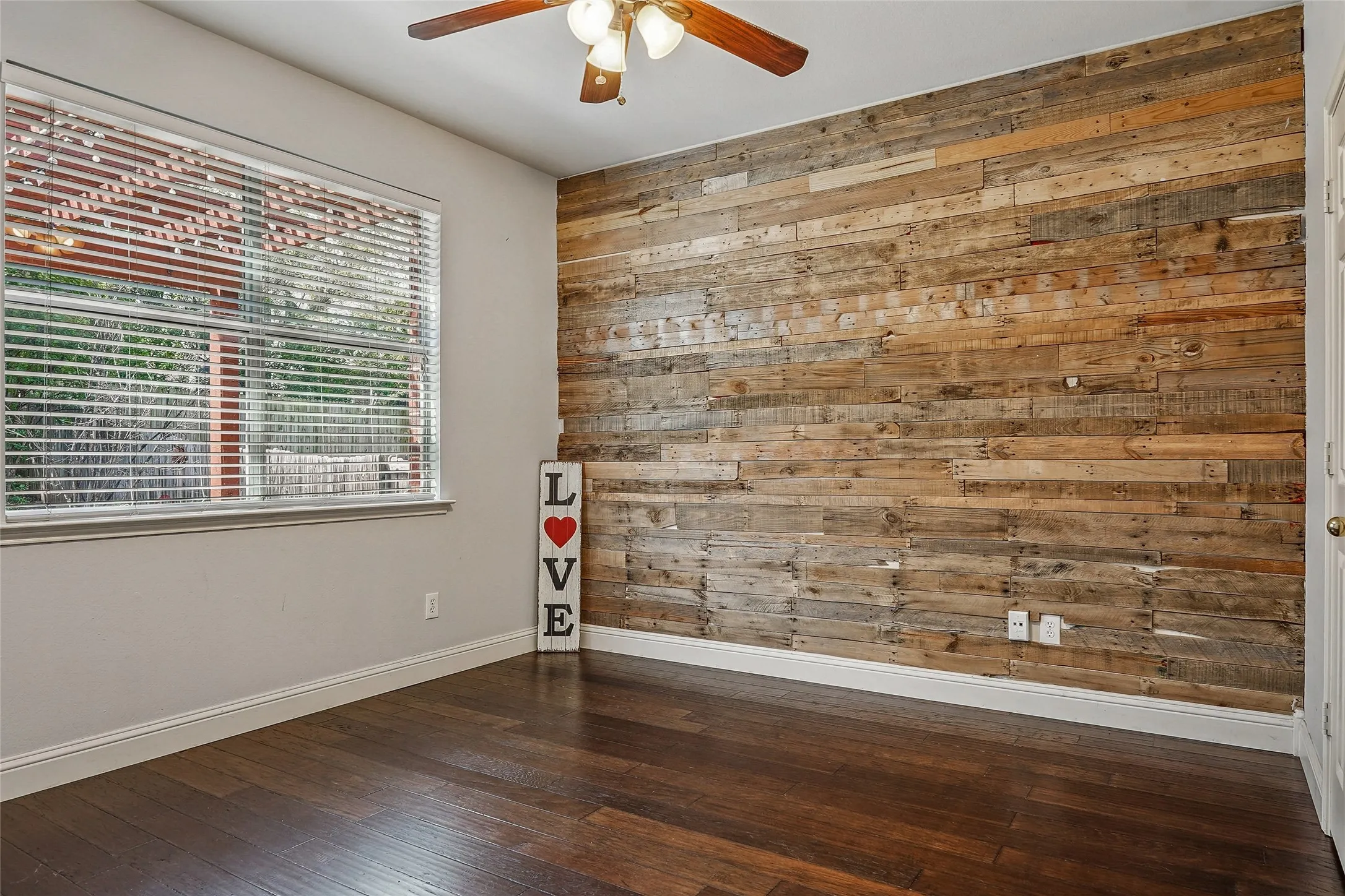 Unfurnished room featuring wooden walls, a ceiling fan, and dark wood-type flooring