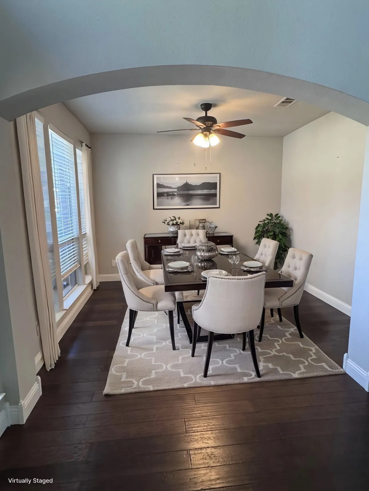 Dining room featuring arched walkways, dark wood-style floors, and a ceiling fan