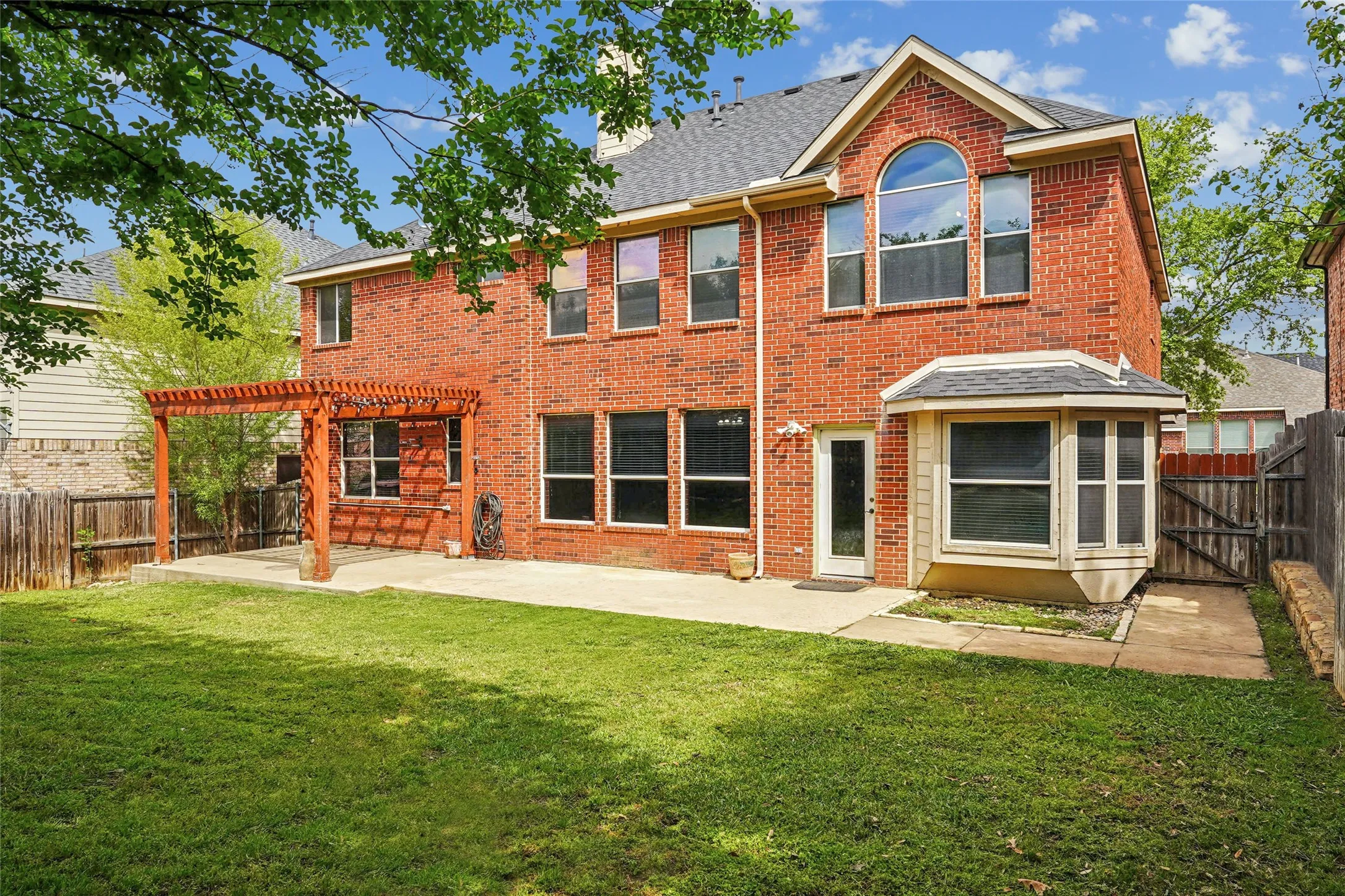 Back of property with a fenced backyard, brick siding, a chimney, a patio area, and a gate