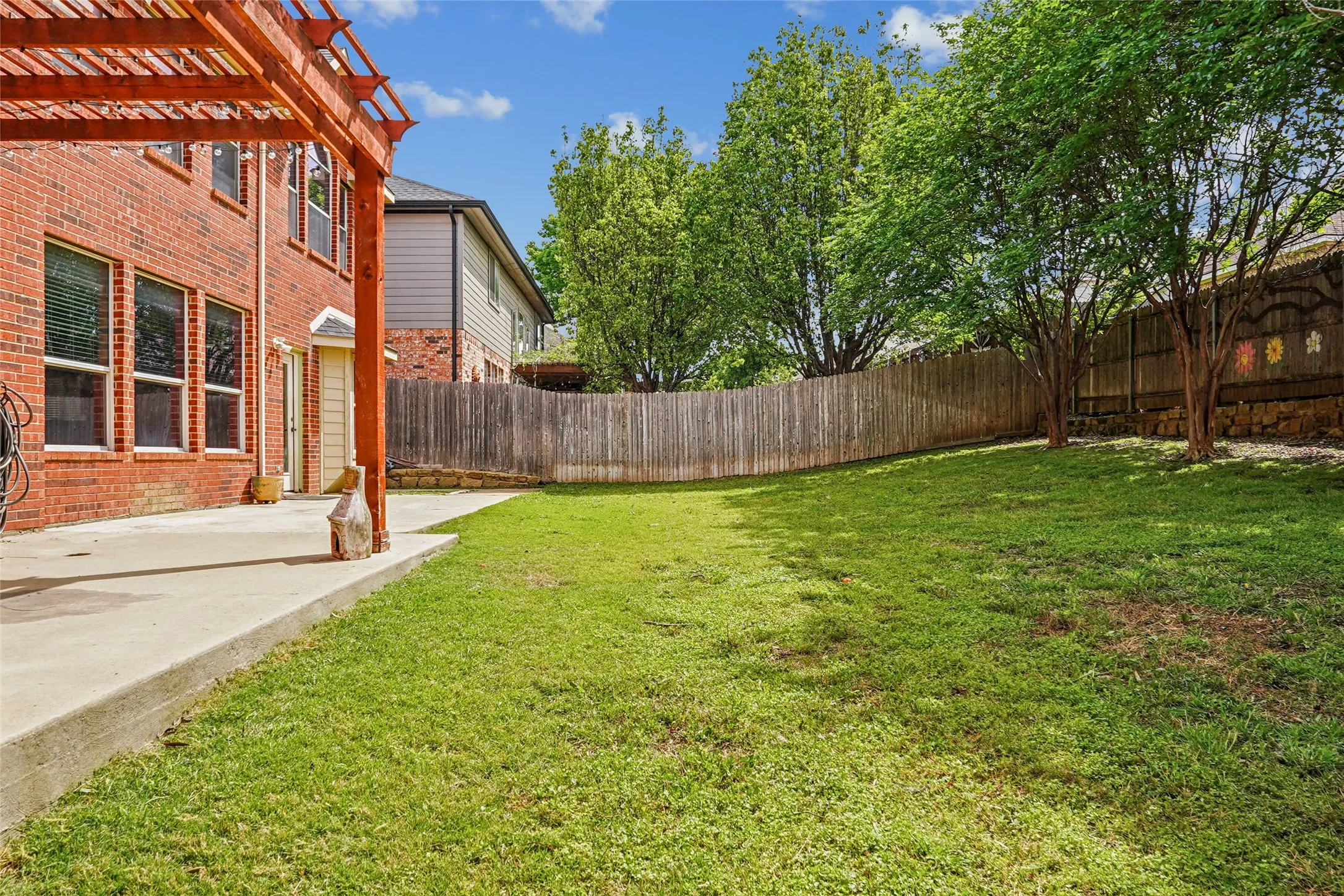 Fenced backyard with a pergola and a patio area