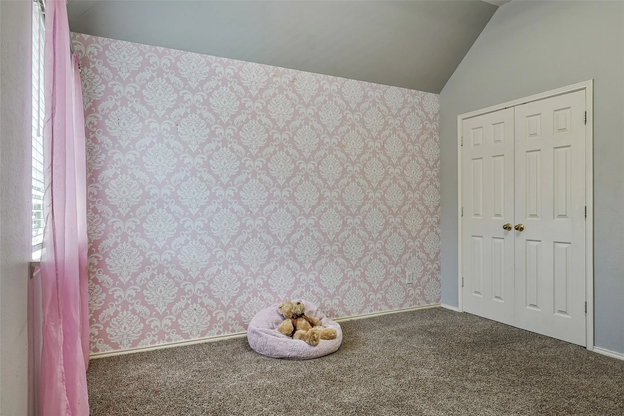 Unfurnished bedroom with wallpapered walls, carpet floors, lofted ceiling, and a closet